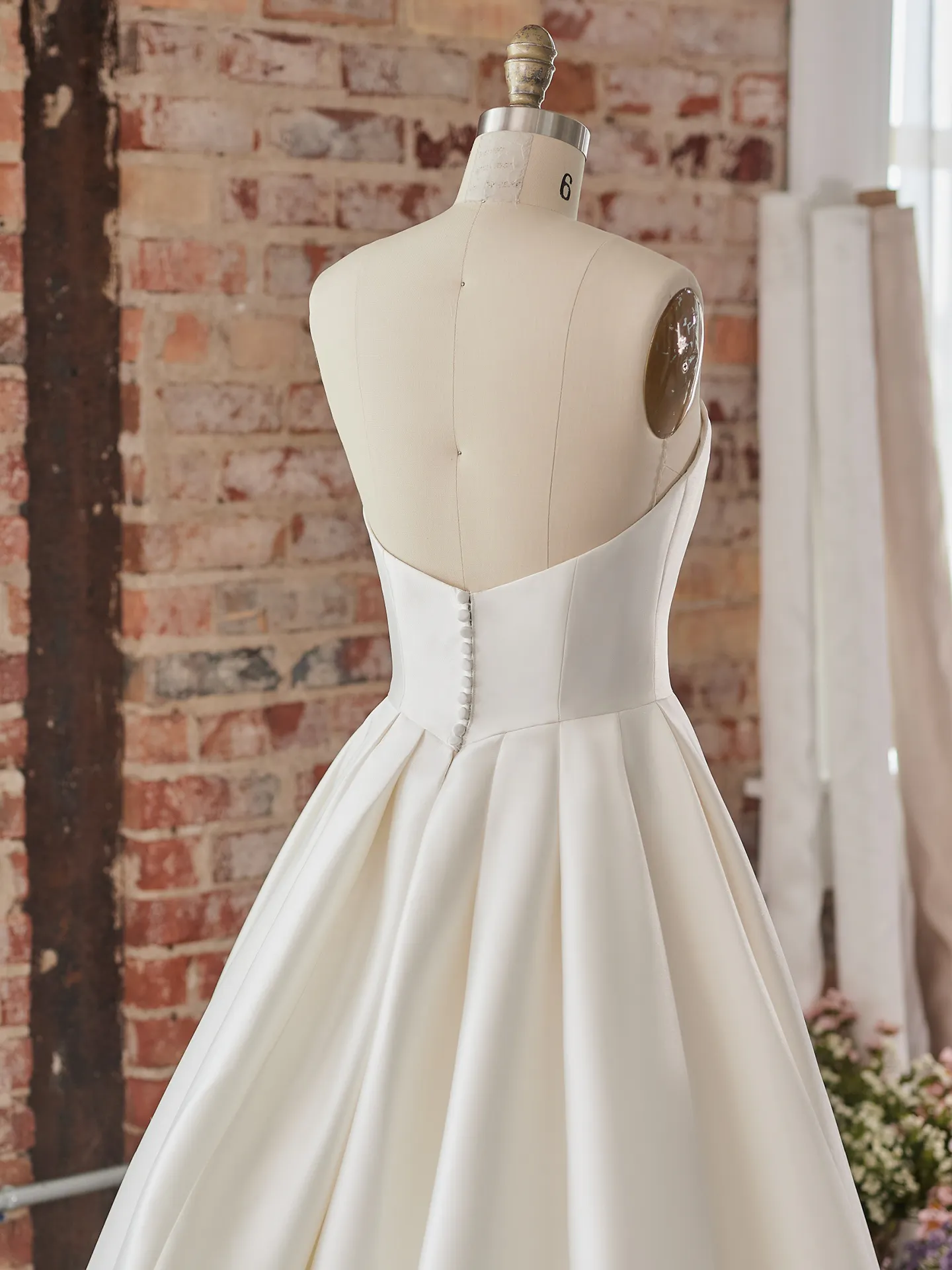 Selena satin A-line wedding dress back view with buttons shown on a mannequin.