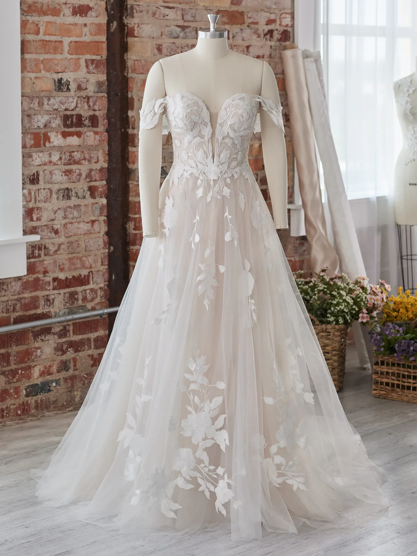 Maggie Sottero Hattie lace off-the-shoulder front view in rustic studio setting