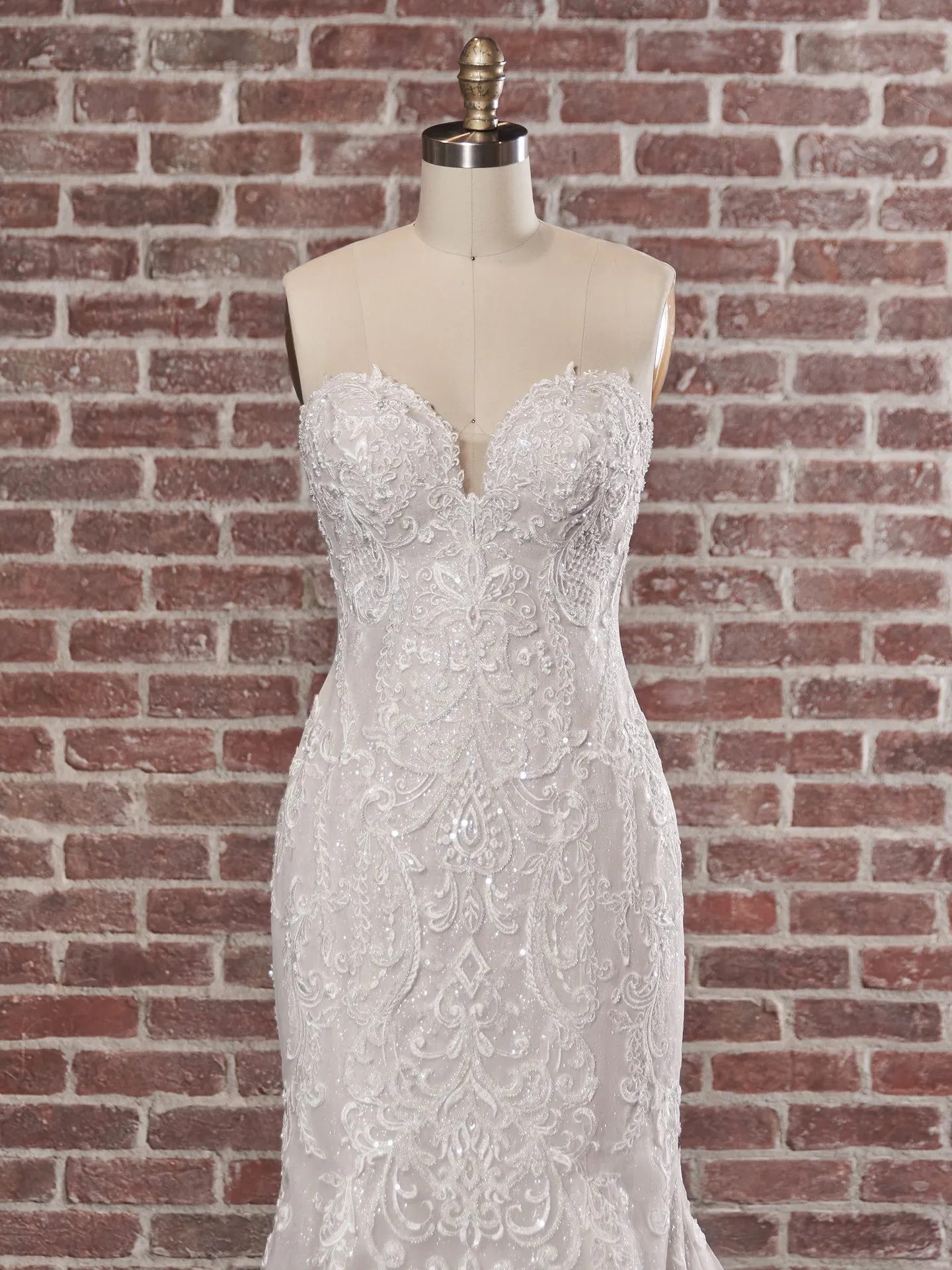 Maggie Sottero Frederique front view elegant bridal dress on mannequin with brick background