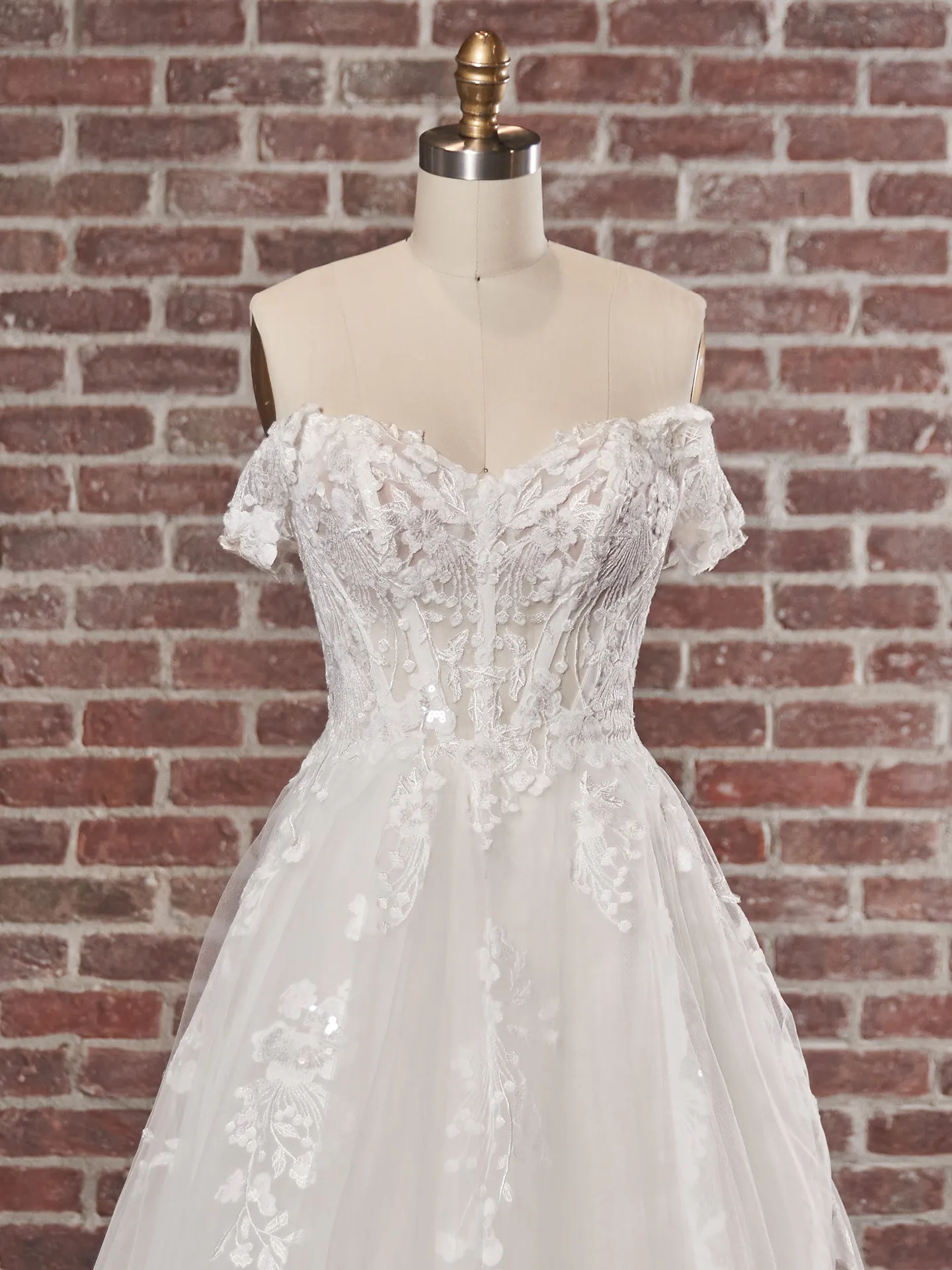 Maggie Sottero Harlem front view off-shoulder lace wedding gown on mannequin