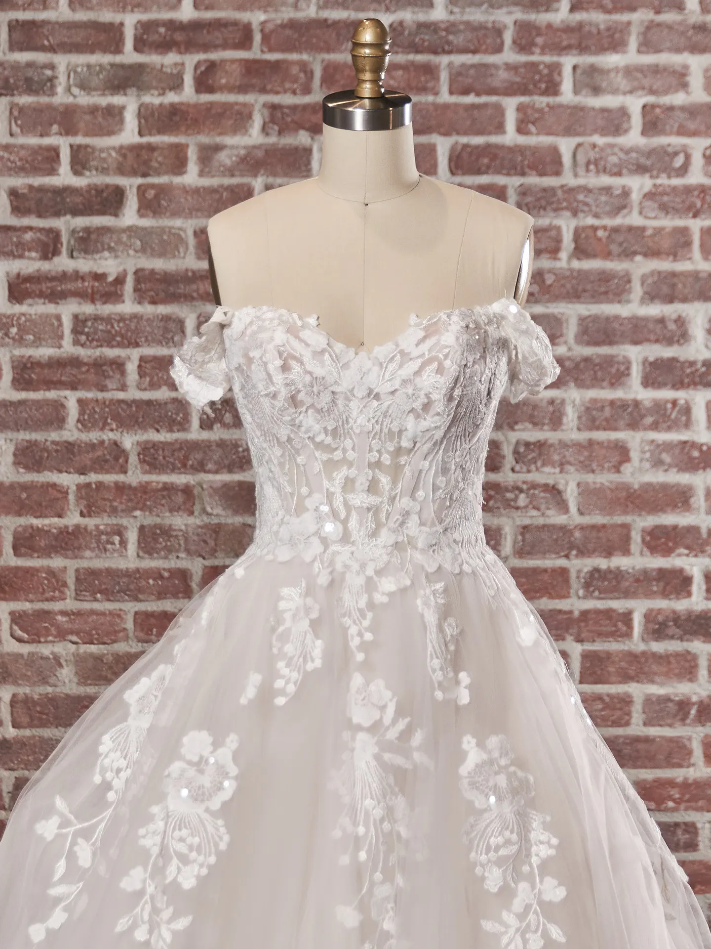 Maggie Sottero Harlem front view off-the-shoulder lace gown on mannequin
