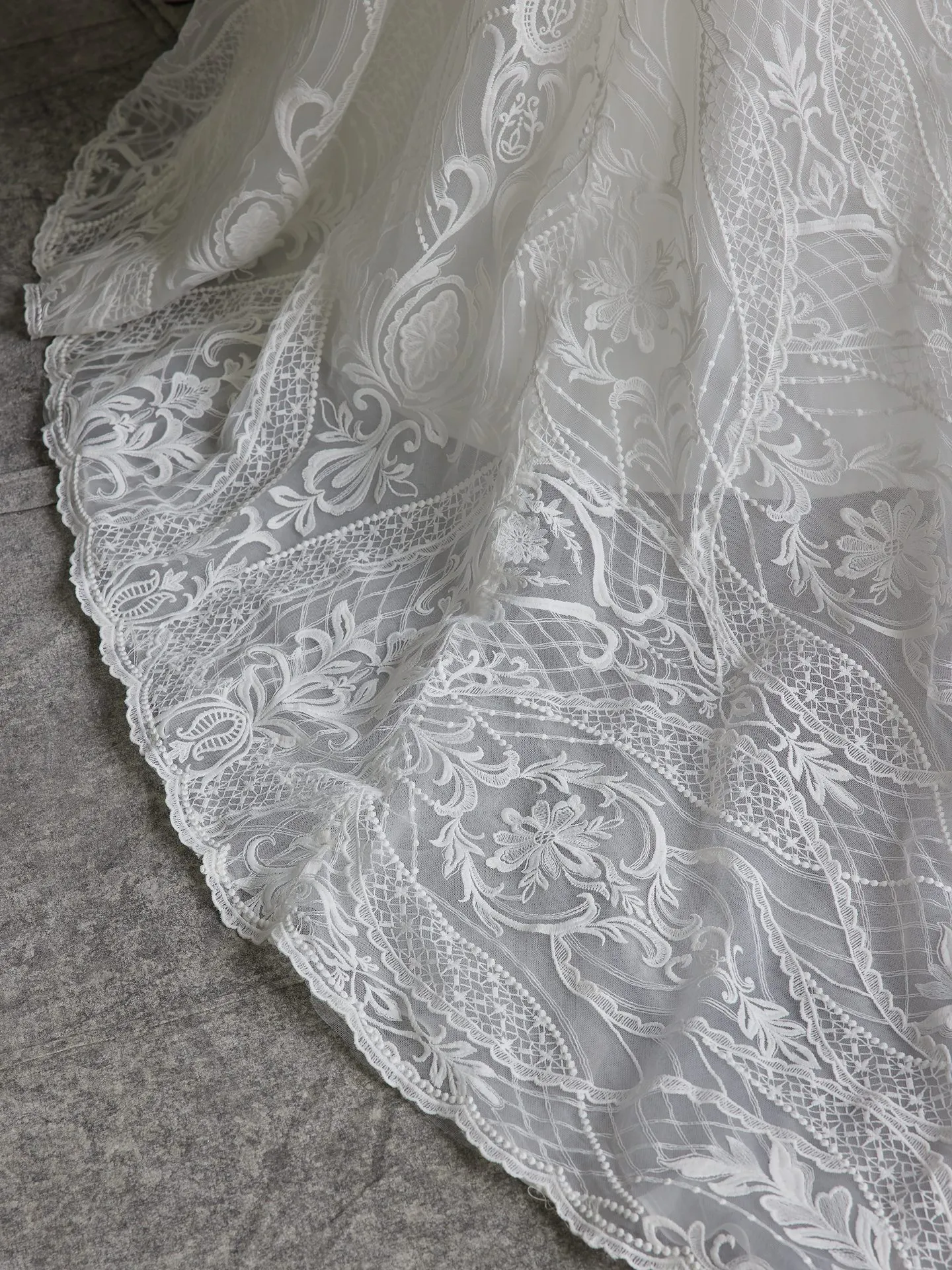 Sottero and Midgley Bronson gown lace detail on gray surface.
