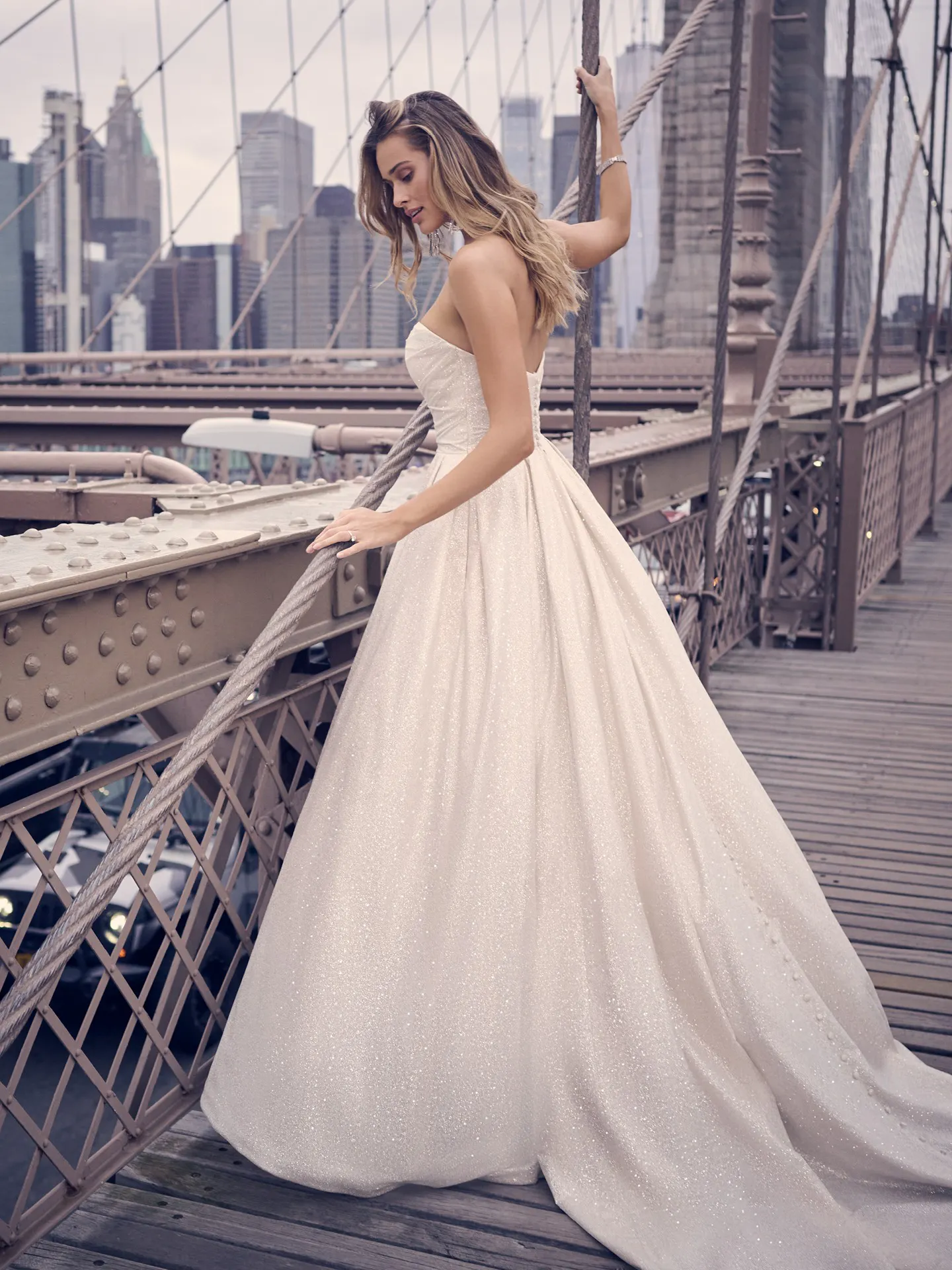 Maggie Sottero Anniston shimmery ballgown side view on bridge.