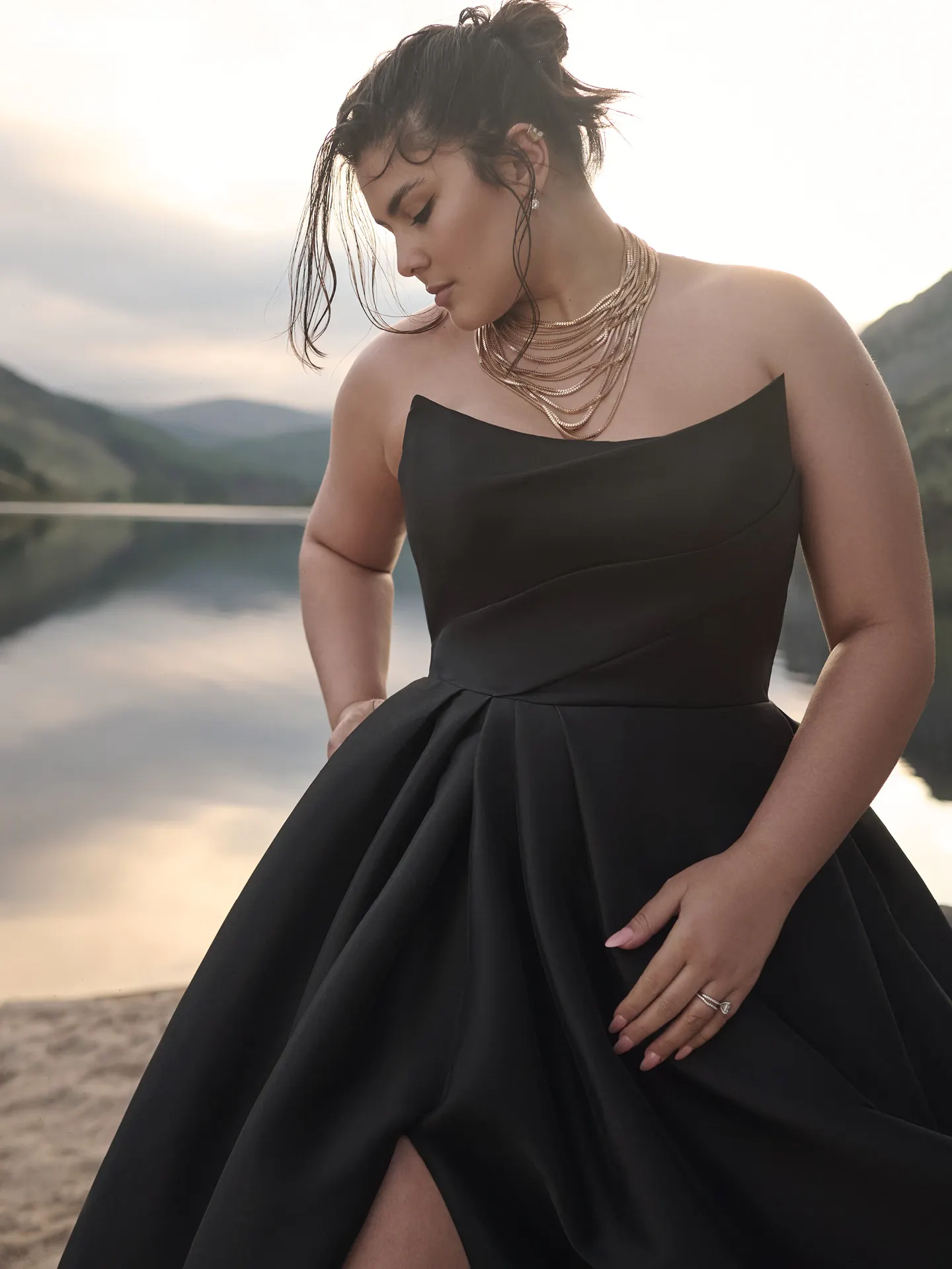 Aspen A-line strapless black gown by Sottero and Midgley, front view by a lake.