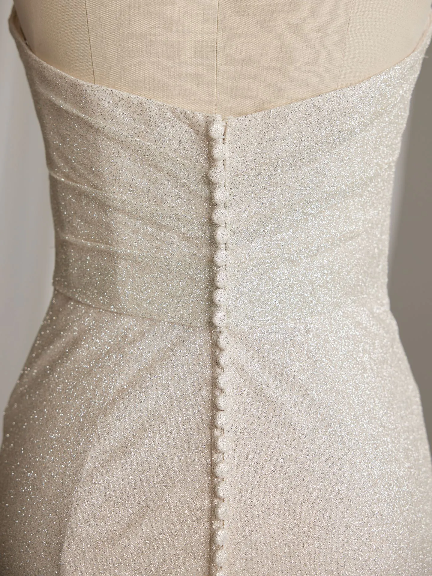 Maggie Sottero glitter bridal gown back view with buttons and fit-and-flare silhouette.