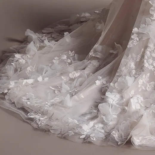 Maggie Sottero Laila gown with 3D floral details, side view of flowing fabric.