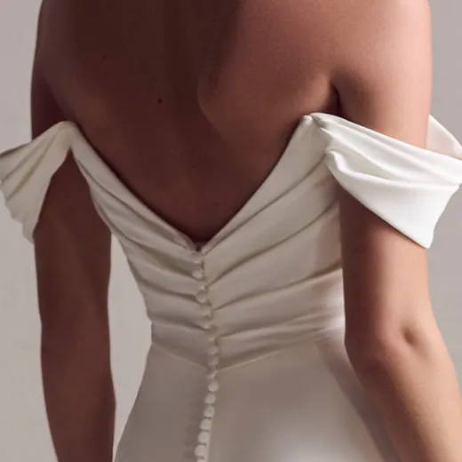 Maggie Sottero crepe wedding dress back view with off-shoulder sleeves and button detail