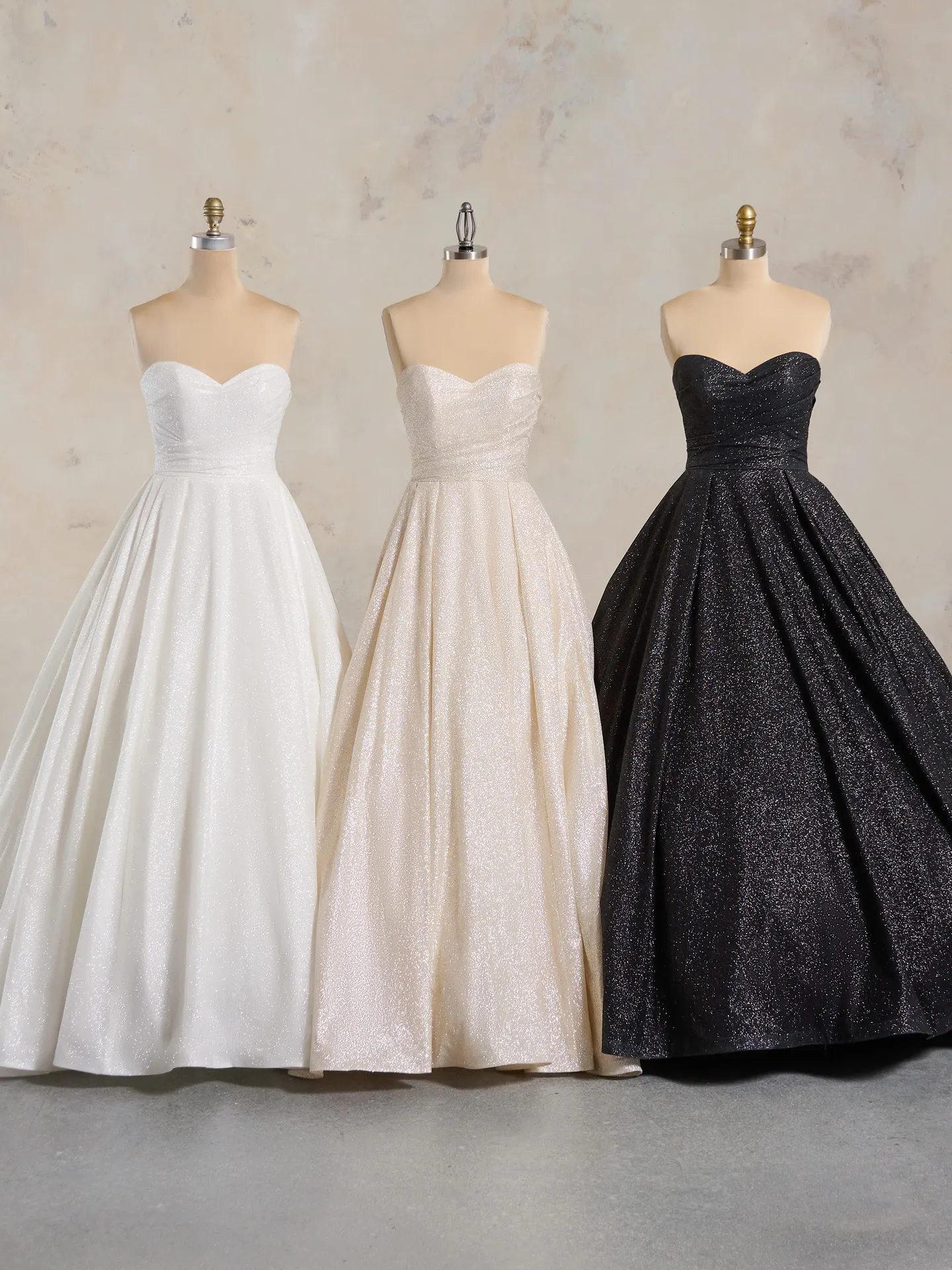 Anniston shimmery ballgown wedding dresses on mannequins in white, blush, and black.