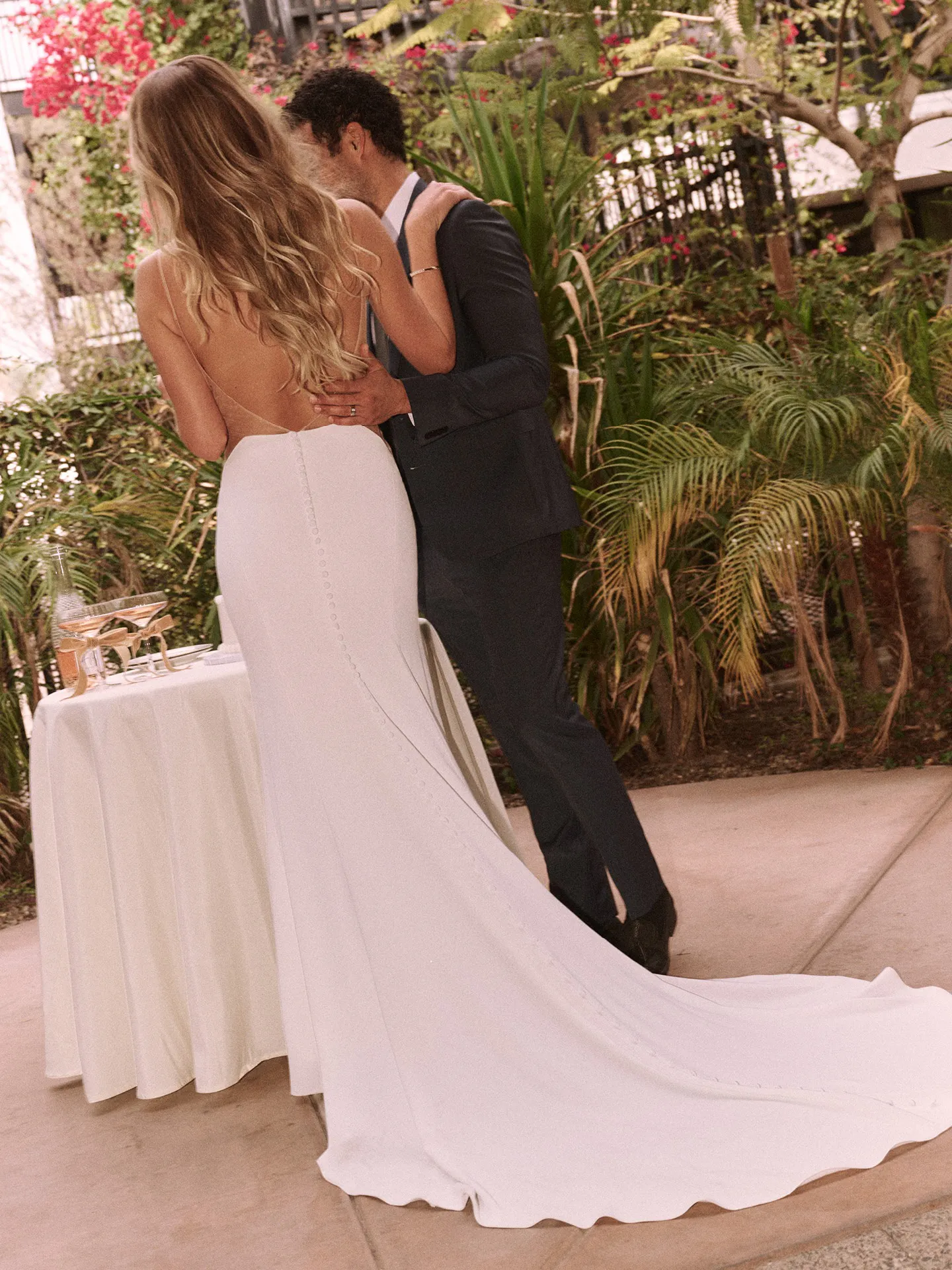 Hope wedding dress, back view; simple design, scoop neckline, outdoors with greenery.