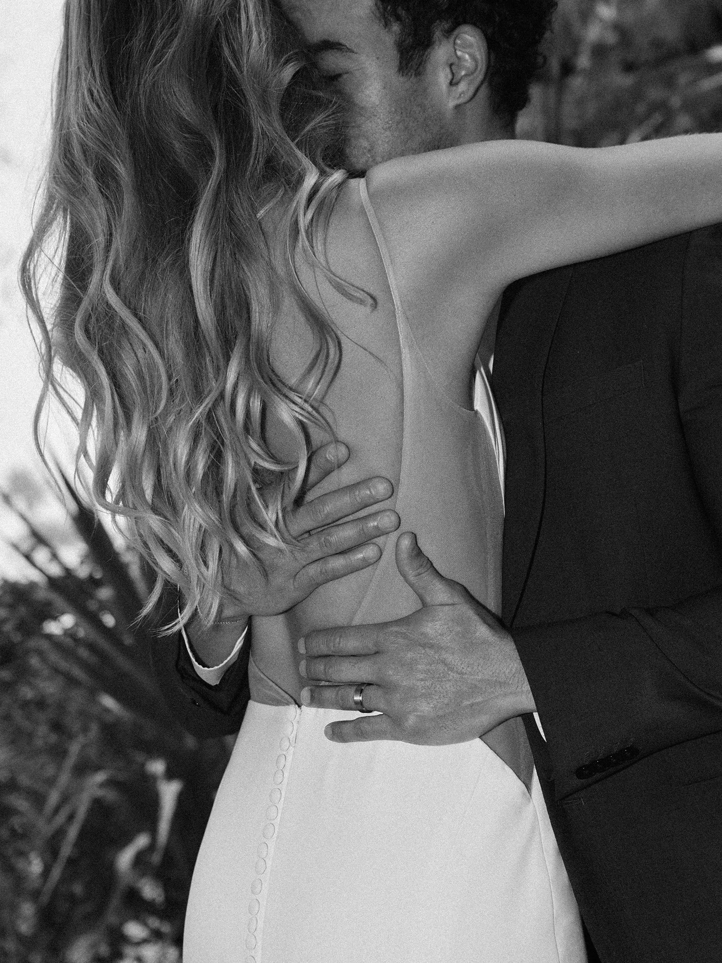 Hope wedding dress side view with scoop back, buttons, and hugging couple.