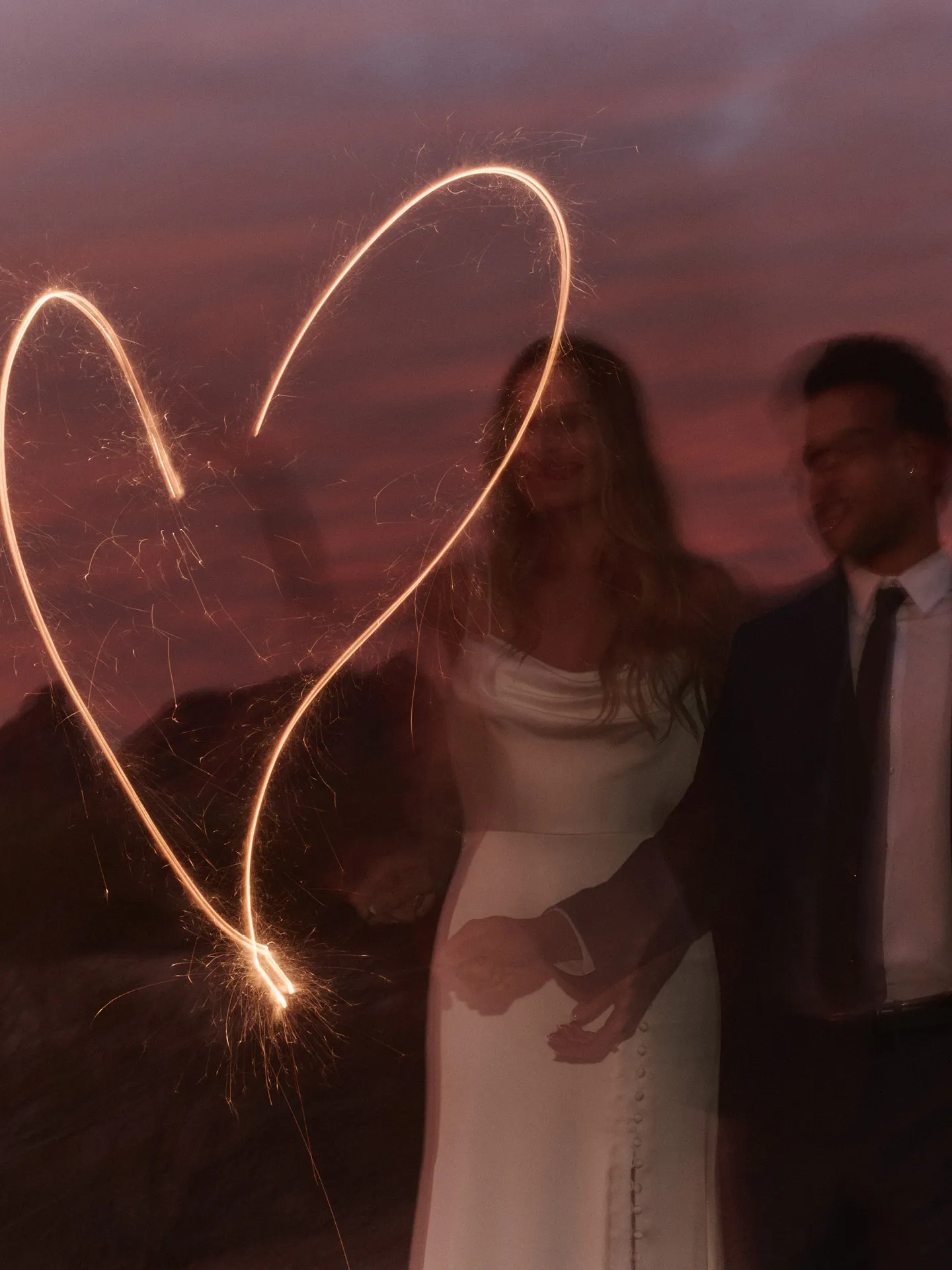 Jett Crepe cowl neck wedding dress, front view with sparklers in night setting.
