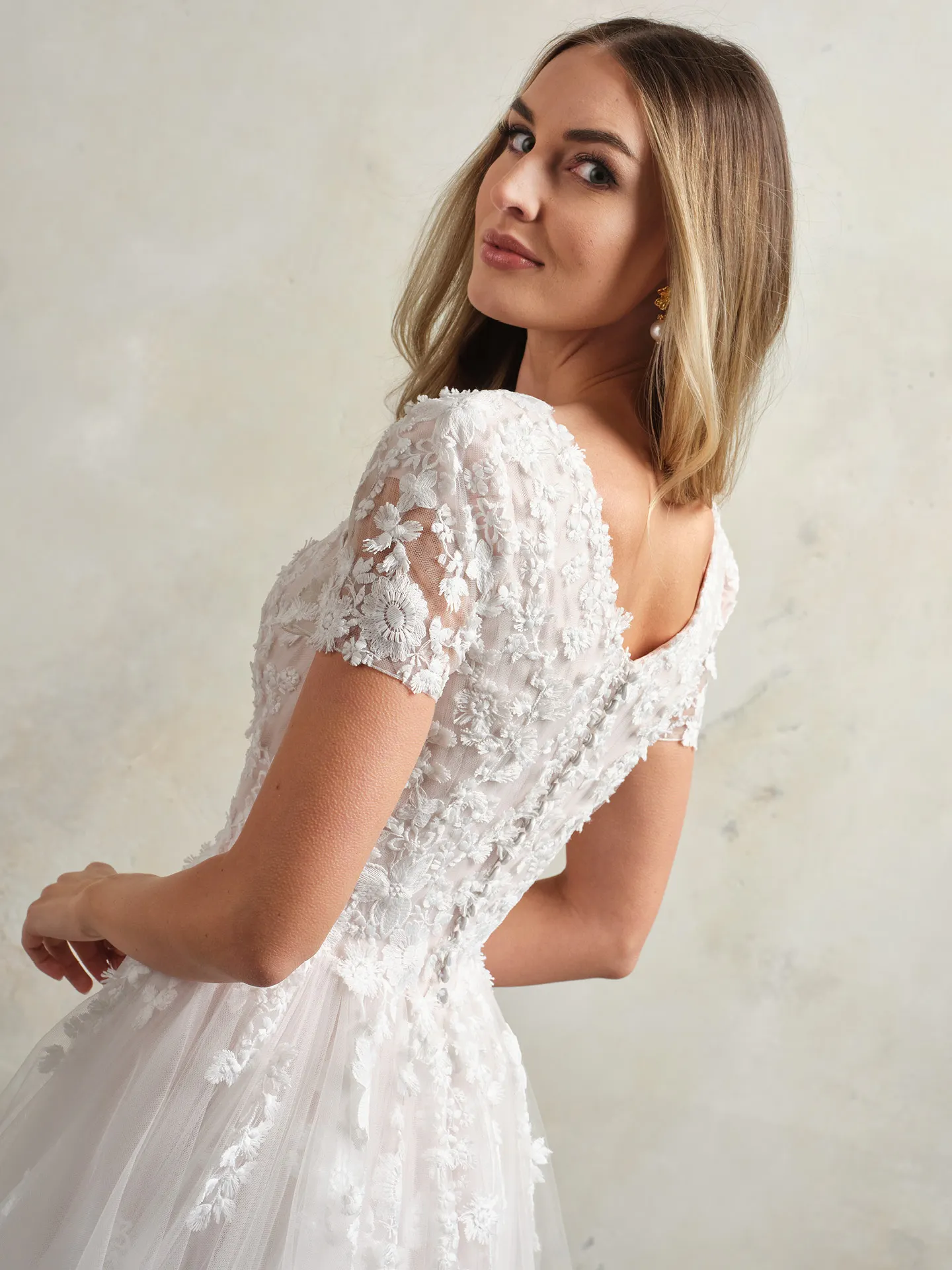 Winona Leigh back view floral lace ball gown bridal dress with short sleeves.