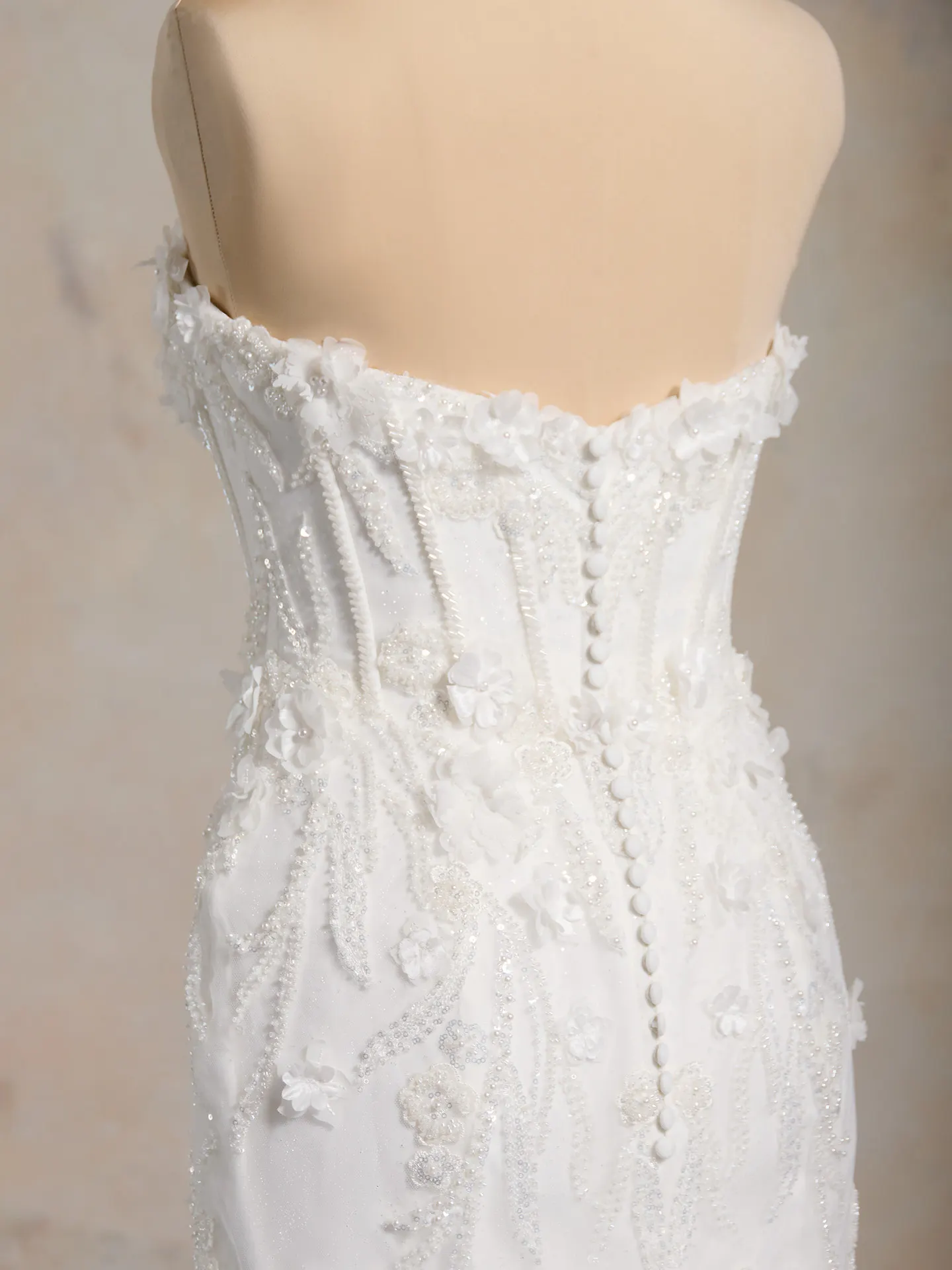 Maggie Sottero back view floral fit-and-flare gown with buttons and bead details.
