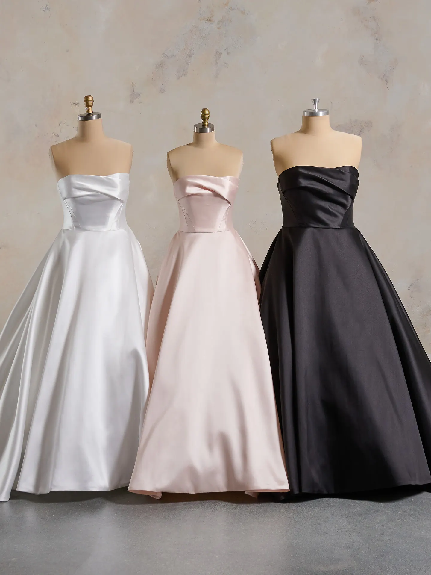 Faro mikado bridal gowns in white, pink, black draped on mannequins front view.