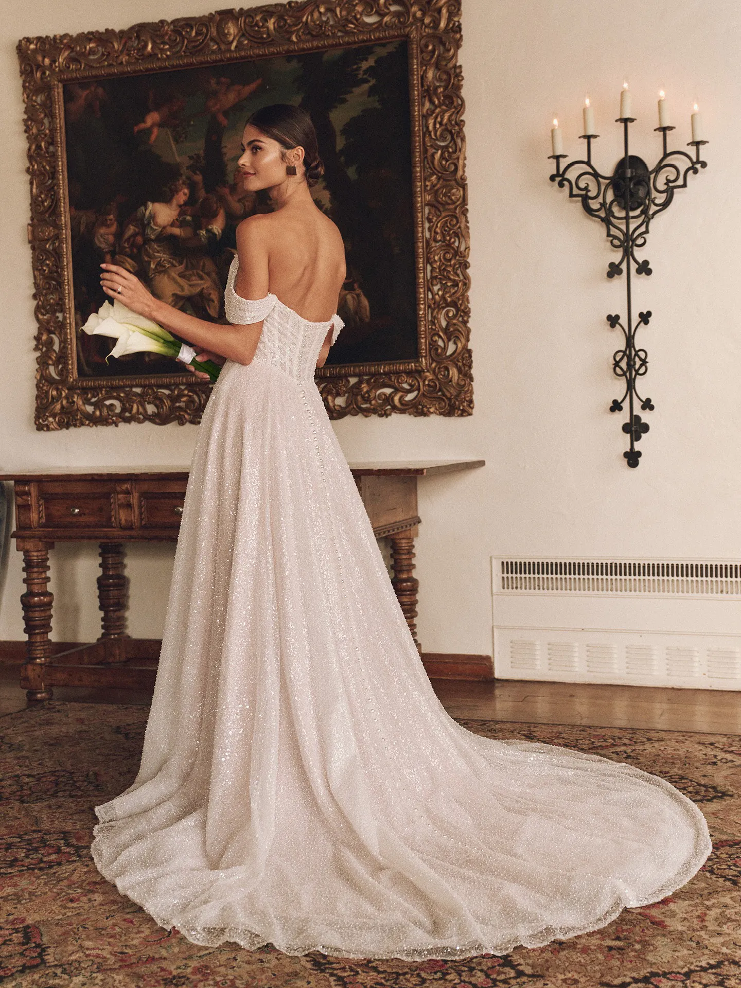 Monica off-the-shoulder gown back view in elegant room.