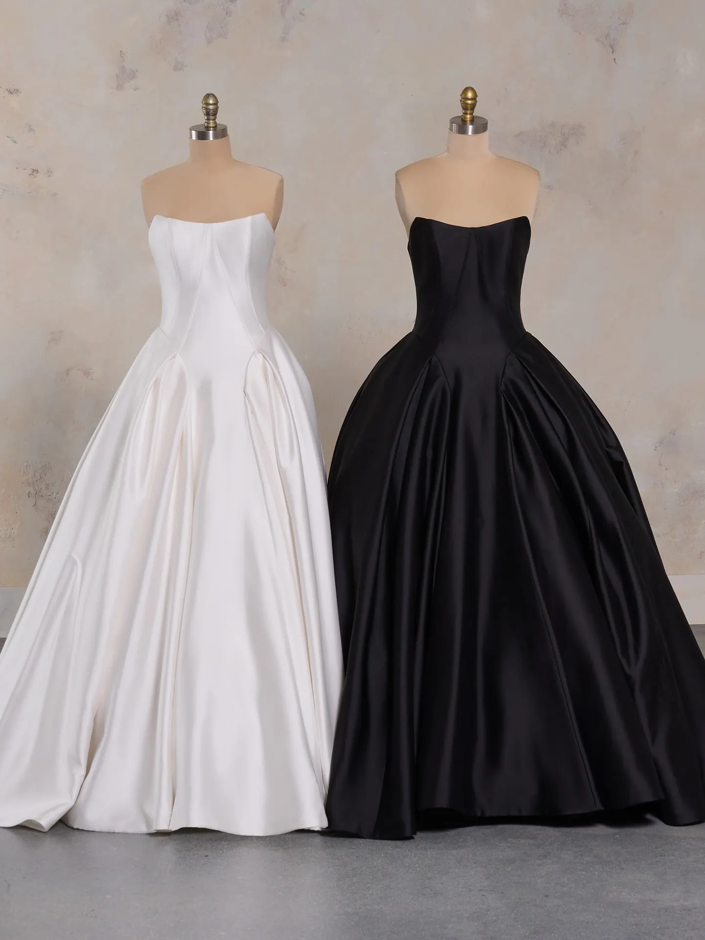 Elegant ballgowns in white and black on mannequins.