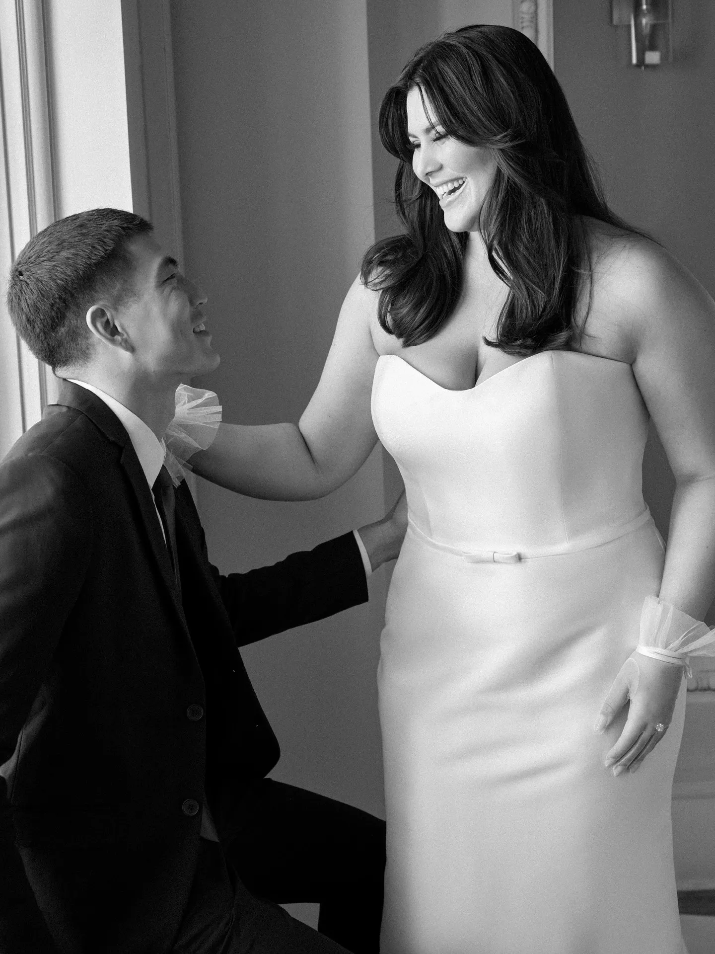 Maggie Sottero Maisie front view wedding gown with bow detail, couple smiling indoors.