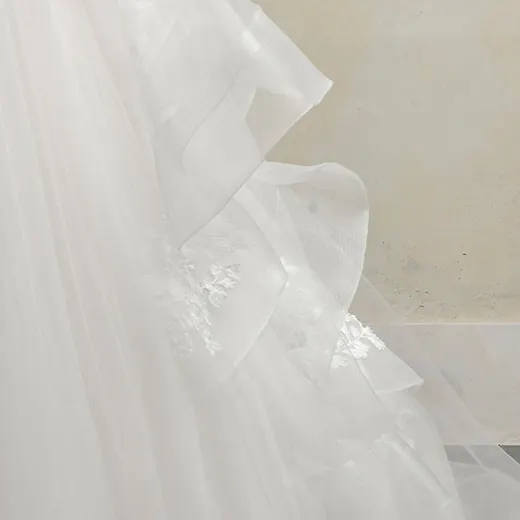 Winona Leigh ball gown close-up with floral lace detail in a soft, layered fabric.