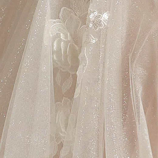 Floral applique on sheer, sparkly Maggie Sottero bridal dress fabric, close-up view.