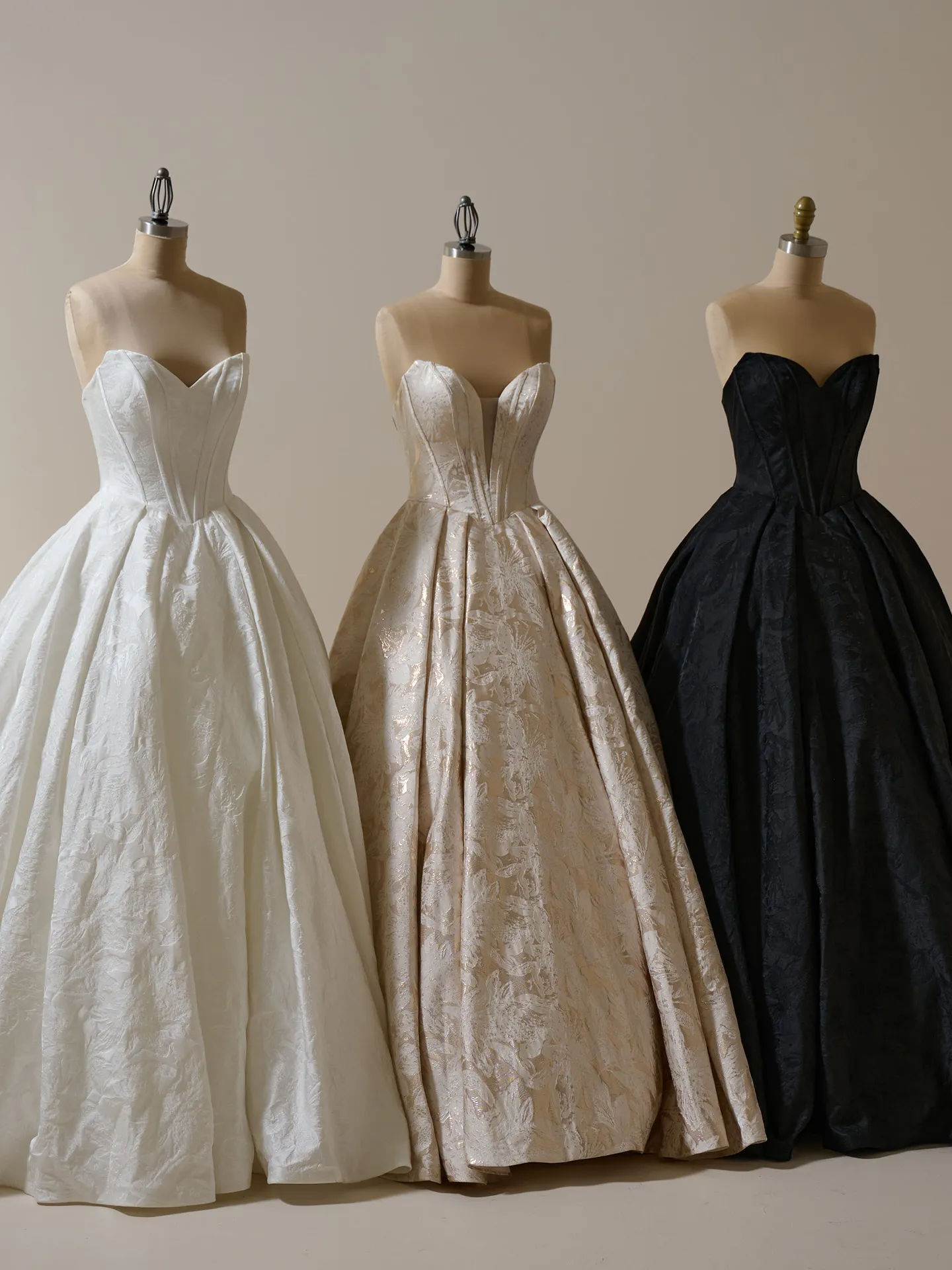 Marie floral ball gown wedding dresses on mannequins in white, gold, and black.