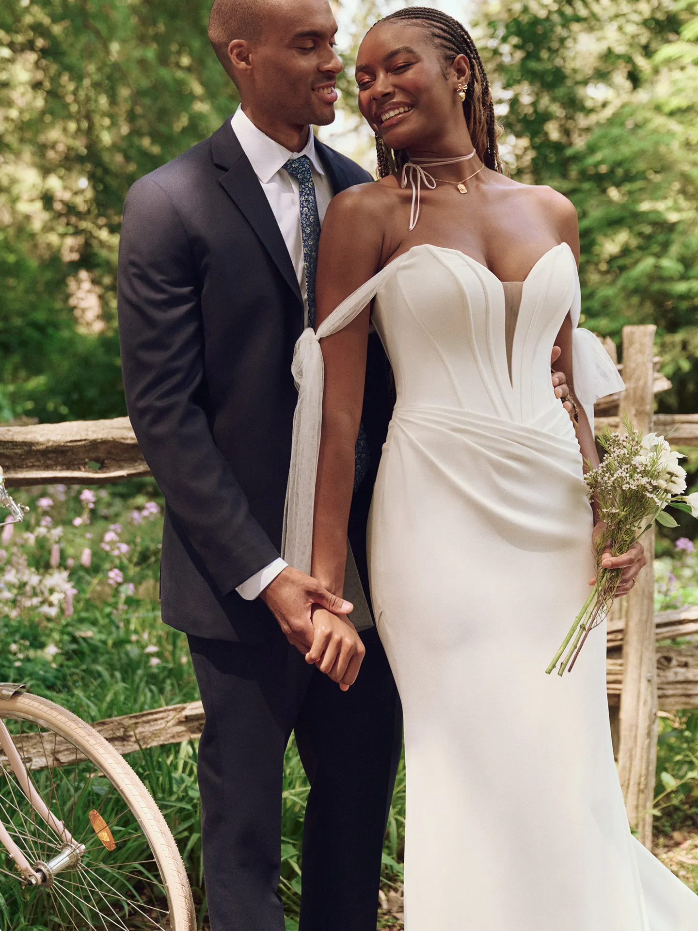 Maggie Sottero Jace front view, exposed boning crepe sheath dress in a garden setting.