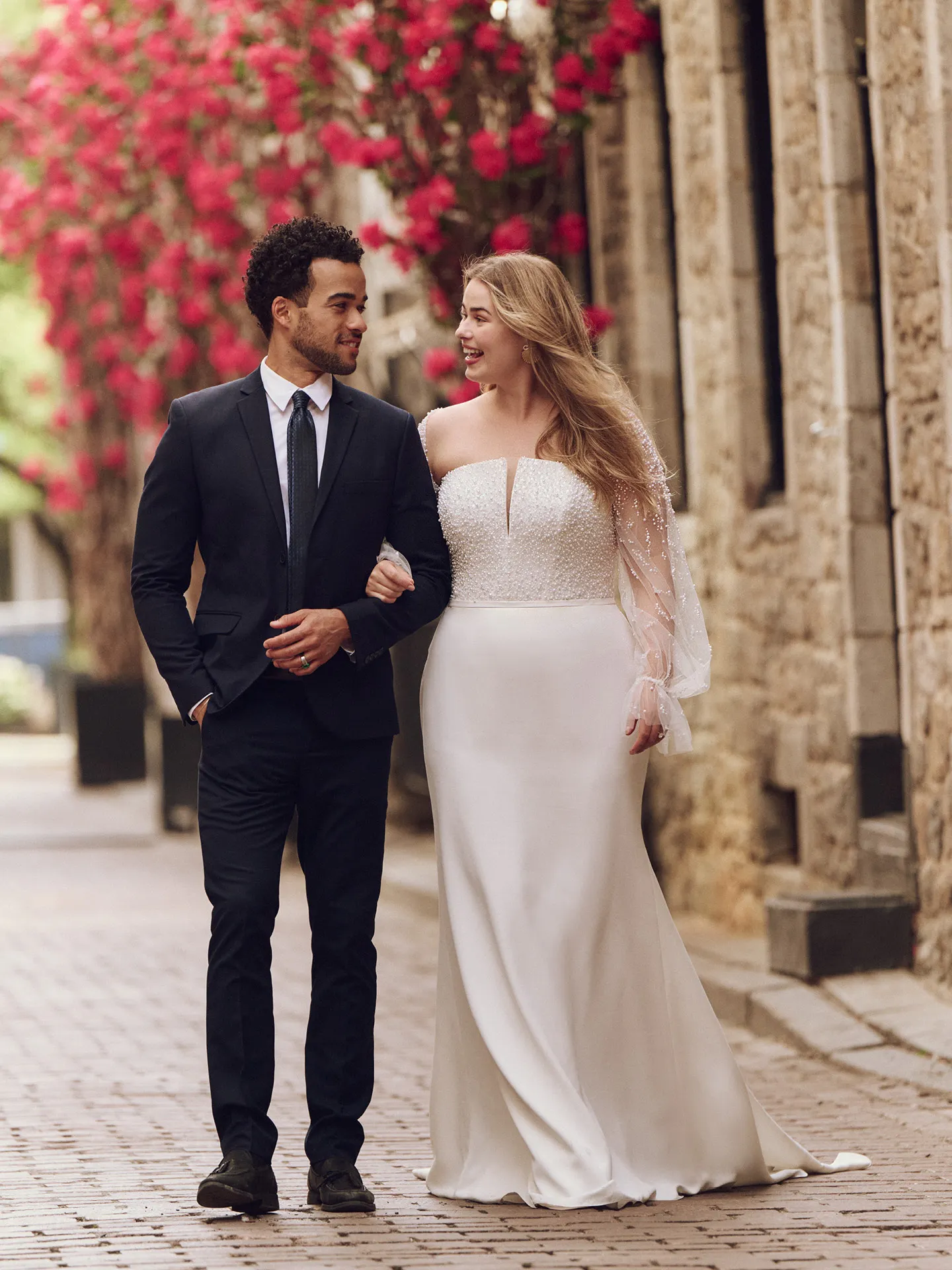 Maggie Sottero Heyda front view on cobblestone street with red flowers