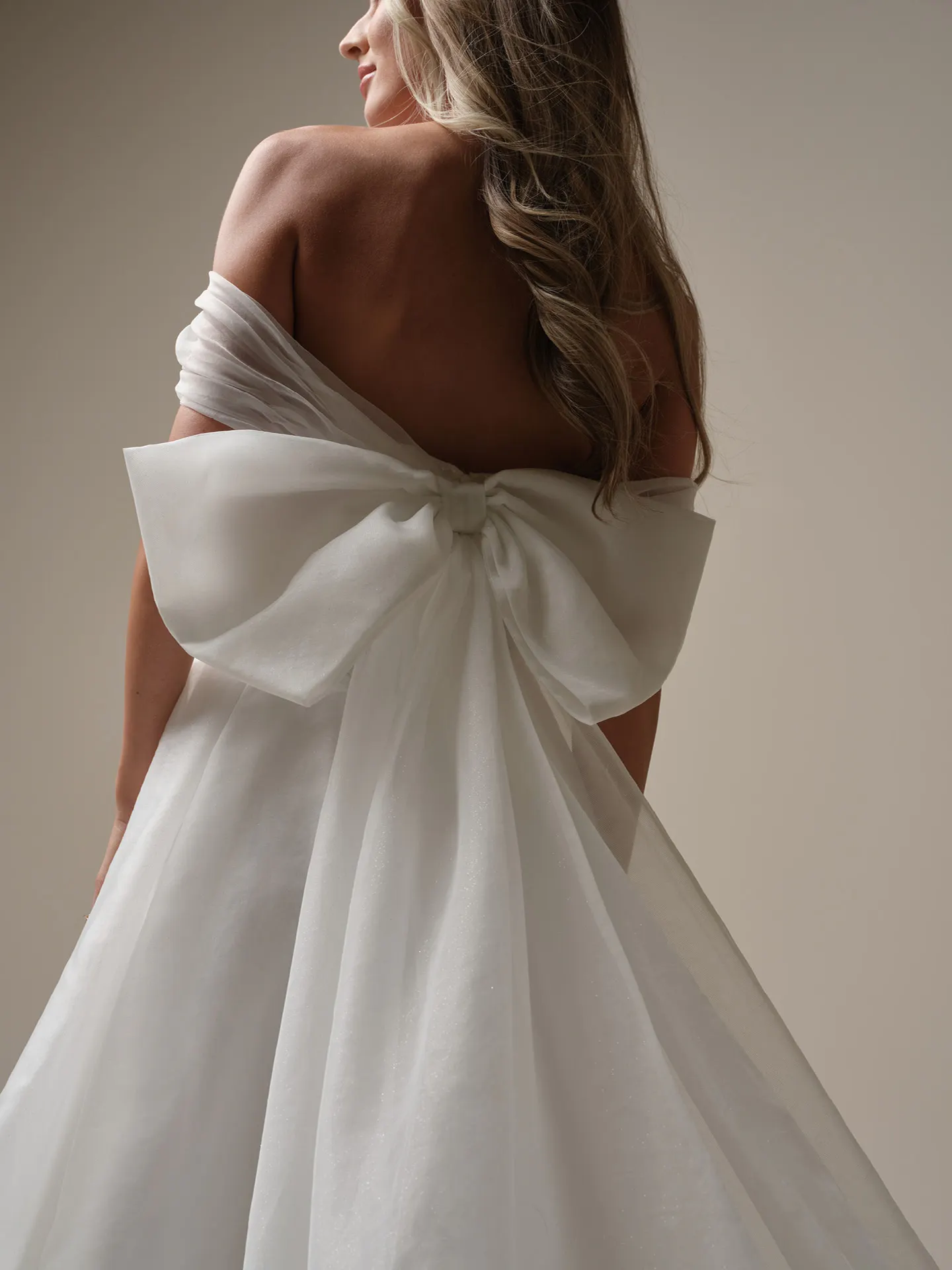 Maggie Sottero Krisha back view with bow and off-the-shoulder wrap.