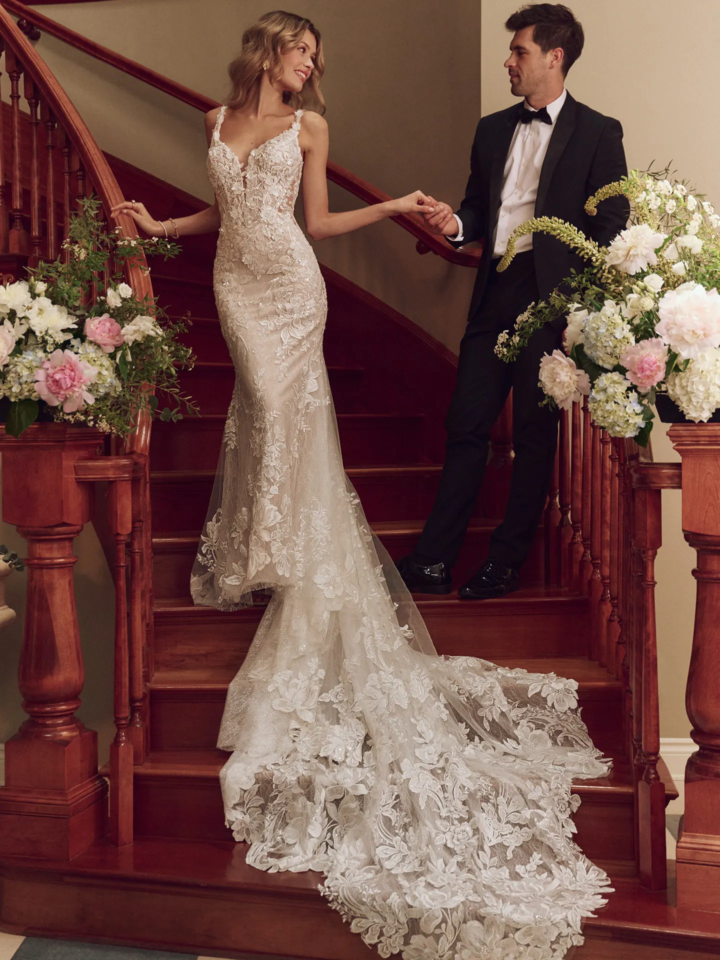 Sottero and Midgley Adrian lace mermaid gown, front view, model on staircase with flowers