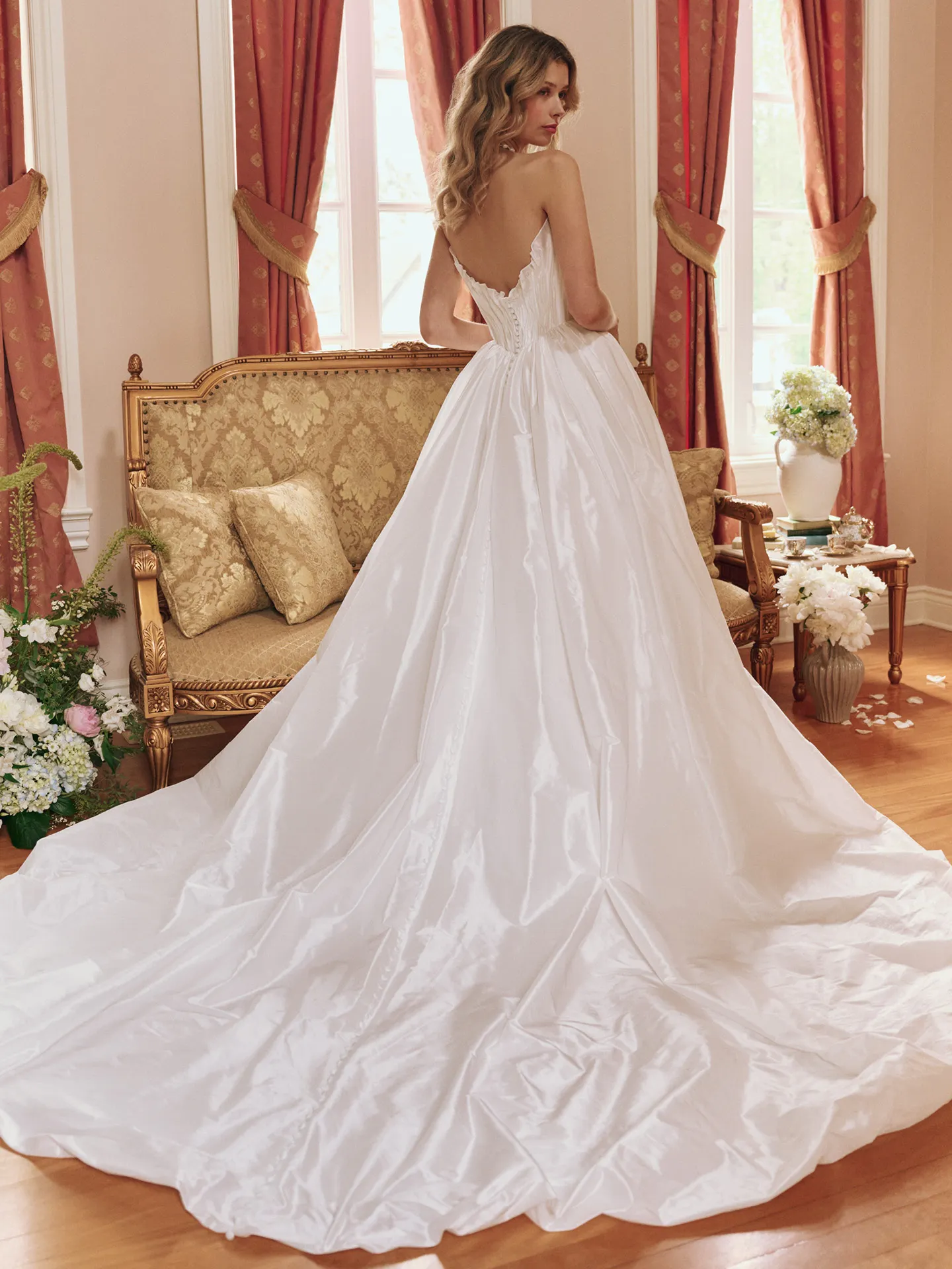 Maggie Sottero Lafayette back view, ruched taffeta bridal dress with ruffle train in elegant room.