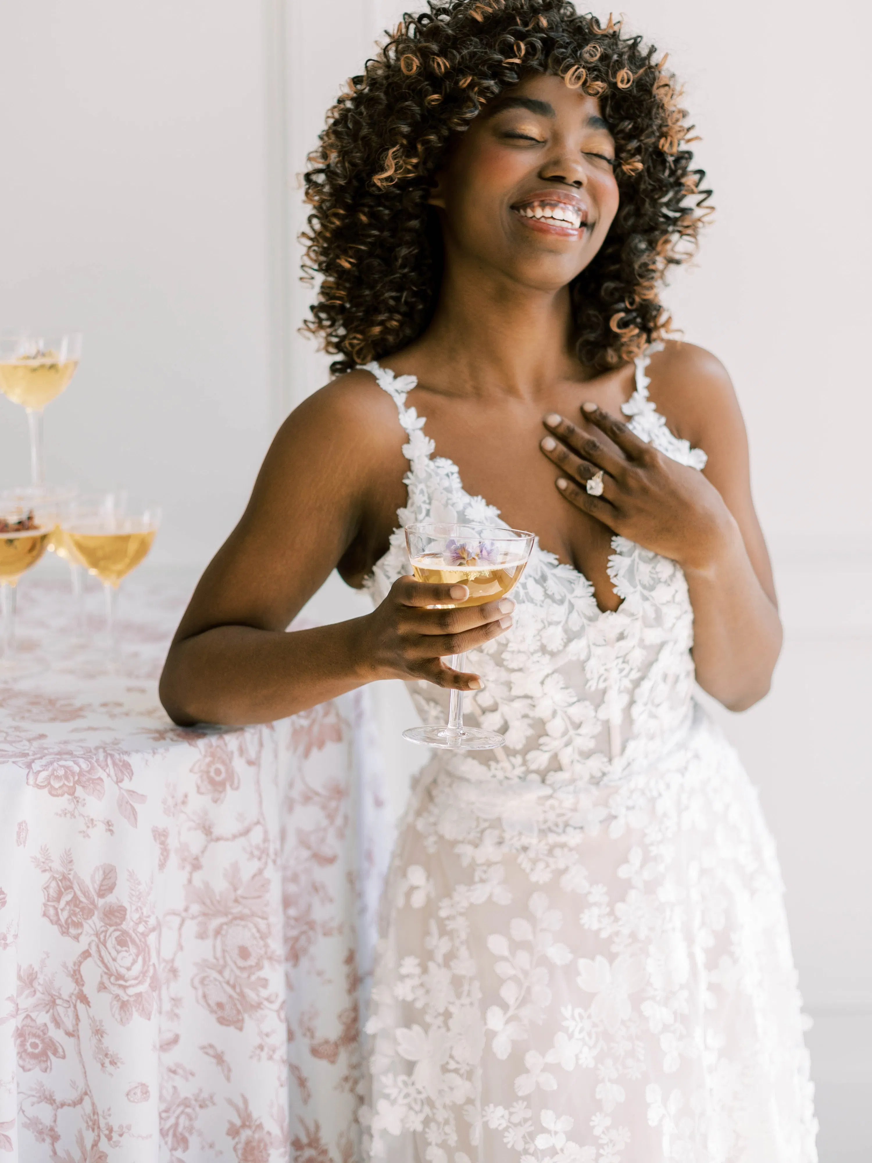 Ladonna floral wedding dress front view by Maggie Sottero with champagne glass.