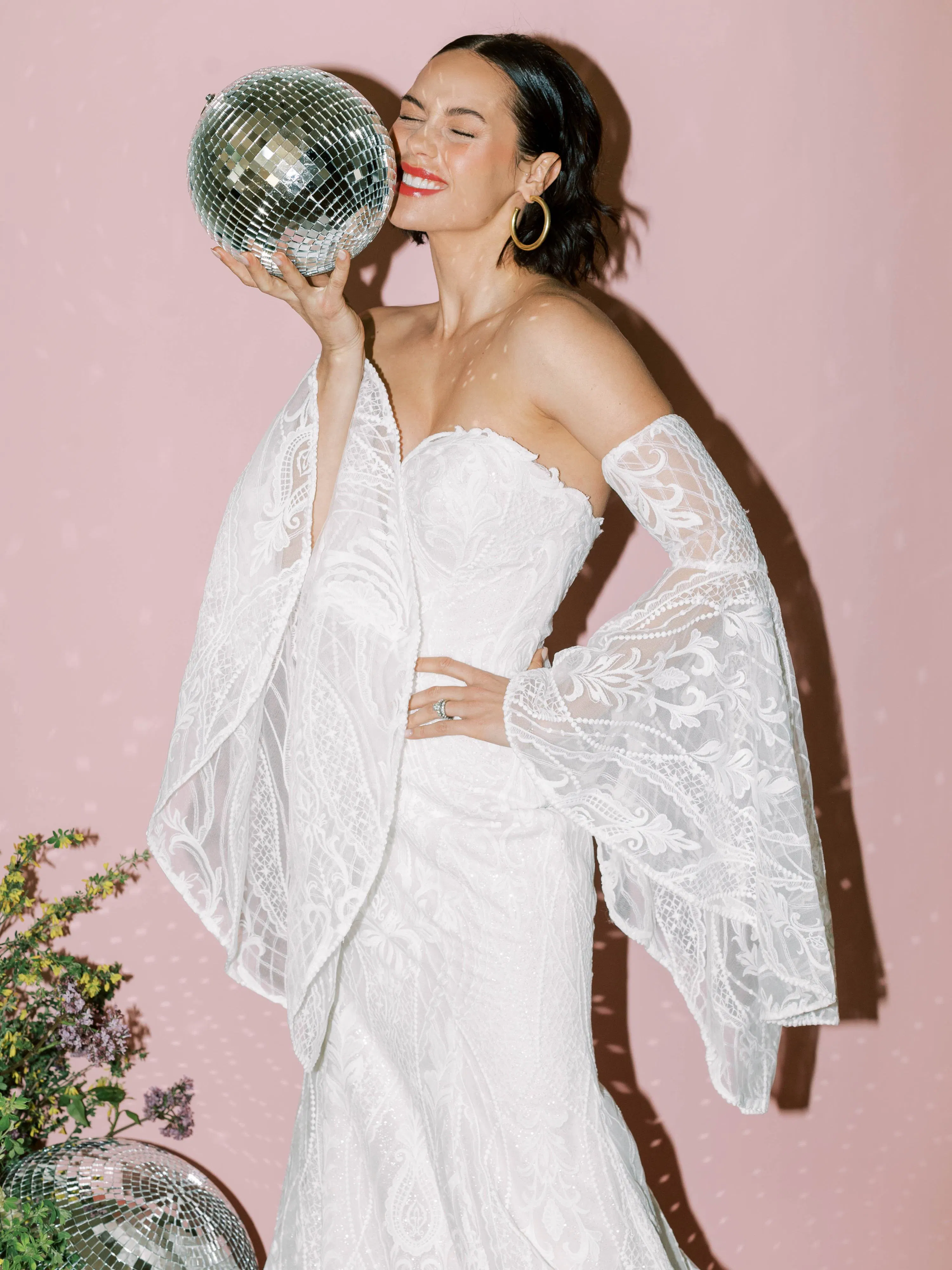 Sottero and Midgley Bronson bridal gown with lace sleeves, model holds a disco ball.