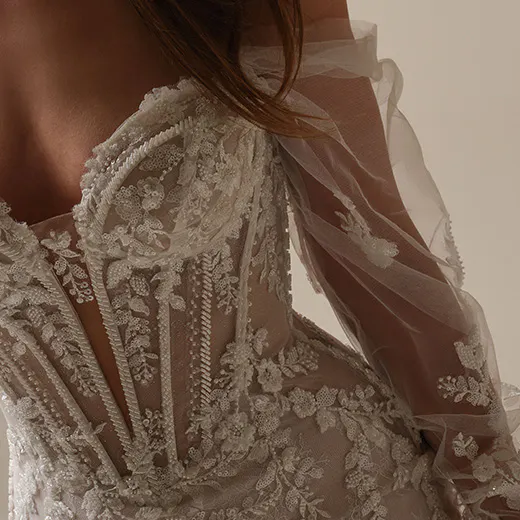 Maggie Sottero Benjie sequin lace close-up showing intricate floral patterns and sheer sleeves.