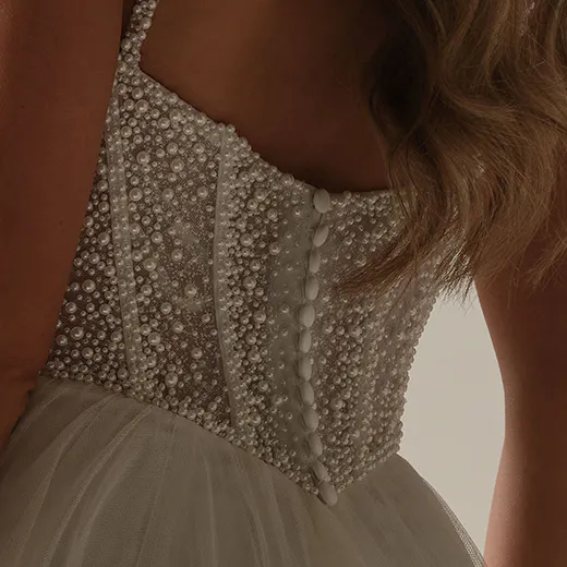 Maggie Sottero Gretchen back view with pearl-embellished corset and tulle A-line skirt.