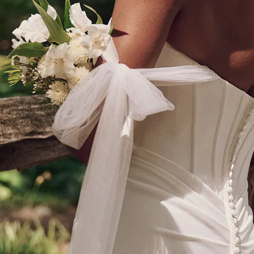 Maggie Sottero Jace back view, exposed boning, crepe sheath dress, bow detail, floral bouquet.