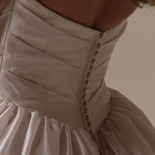 Maggie Sottero Paris back view with asymmetrical basque waist and button detail.