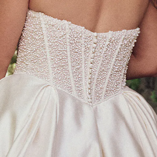 Maggie Sottero Tina back view with pearl-embellished corset and satin ball gown skirt.