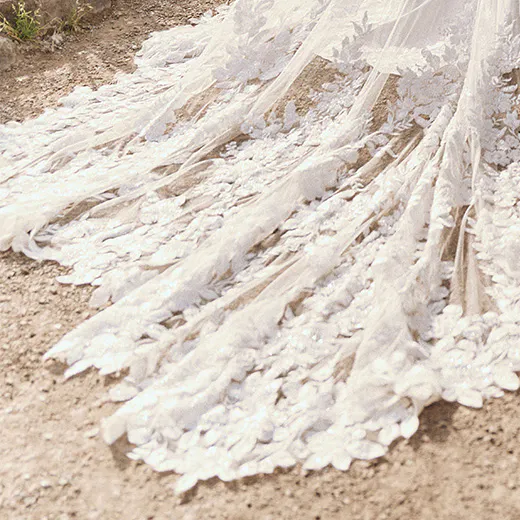 Maggie Sottero Yara train detail with lace applique on a sheath bridal dress, outdoor setting