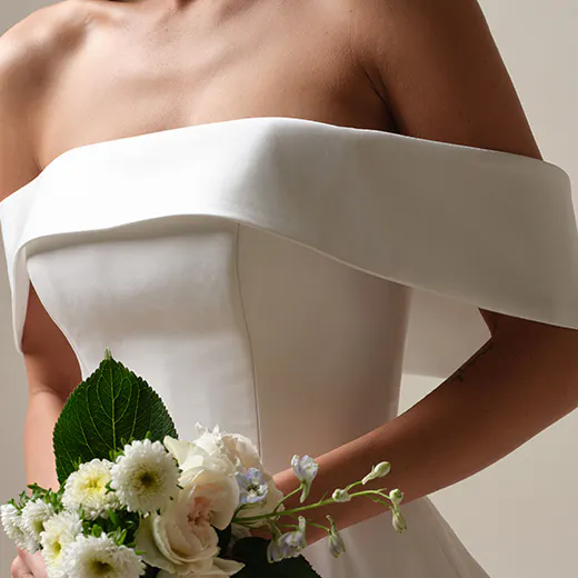 Maggie Sottero Perri front view with banded cuff A-line design, holding bouquet.