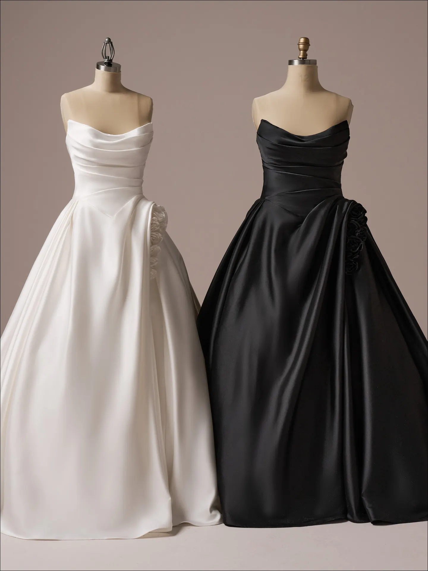 Two strapless ballgown dresses, one white, one black, side by side on mannequins