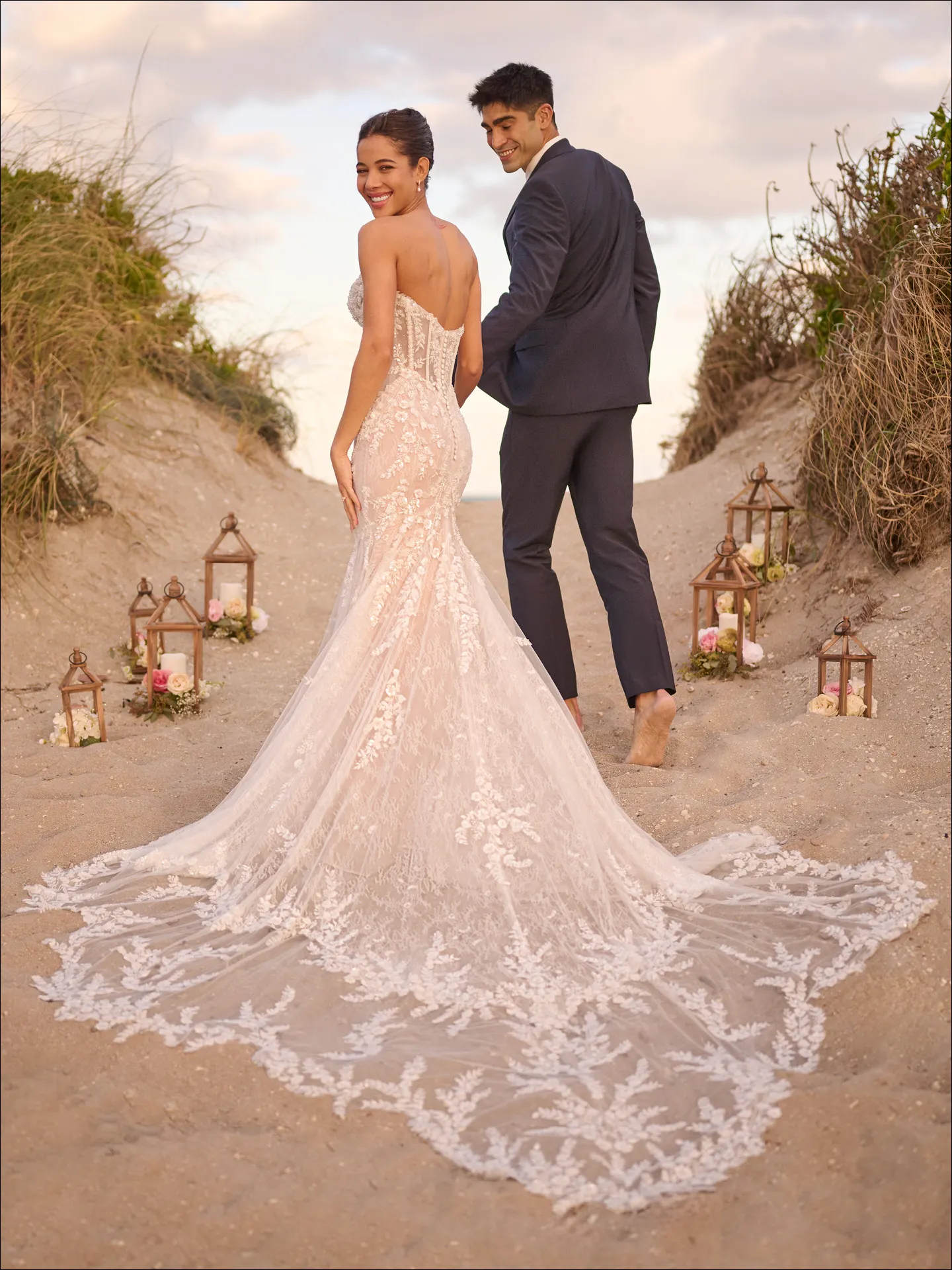 Maggie Sottero Benjie Royale back view, shimmer beaded mermaid dress on sandy path with lanterns