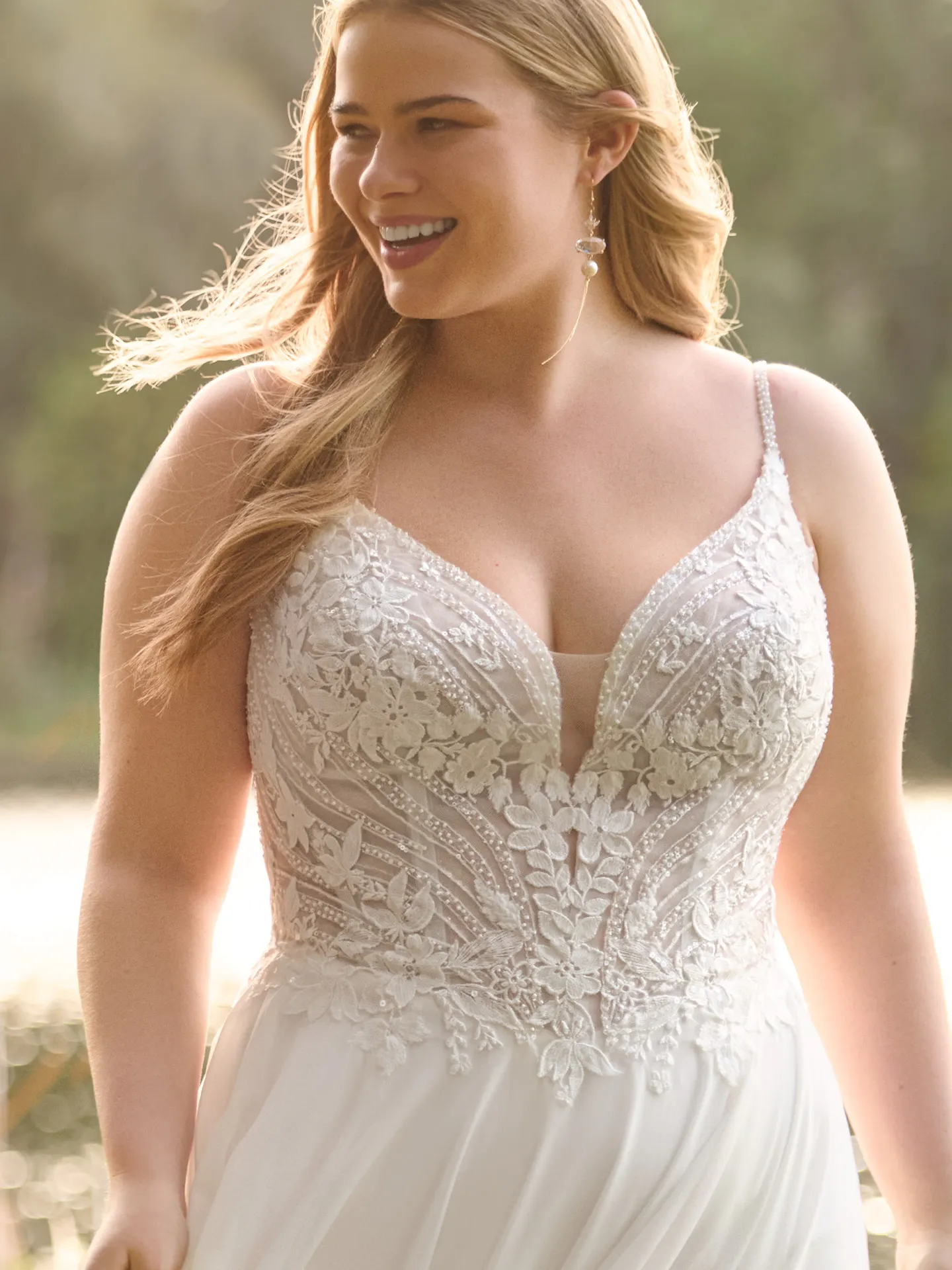 Rebecca Ingram Finley front view, lace bodice, plunge neckline, A-line gown in natural setting.