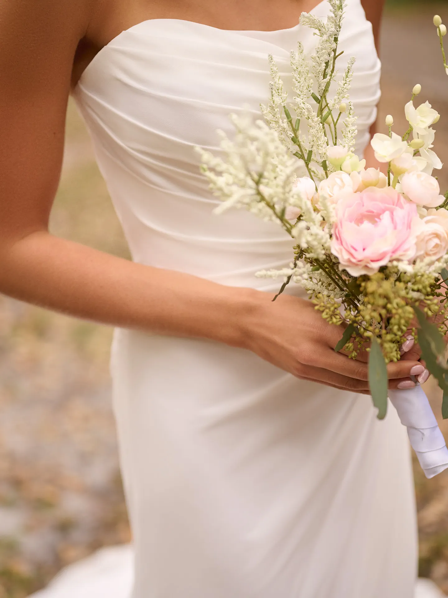 Rebecca Ingram Francesca chiffon sheath wedding dress with a bouquet.