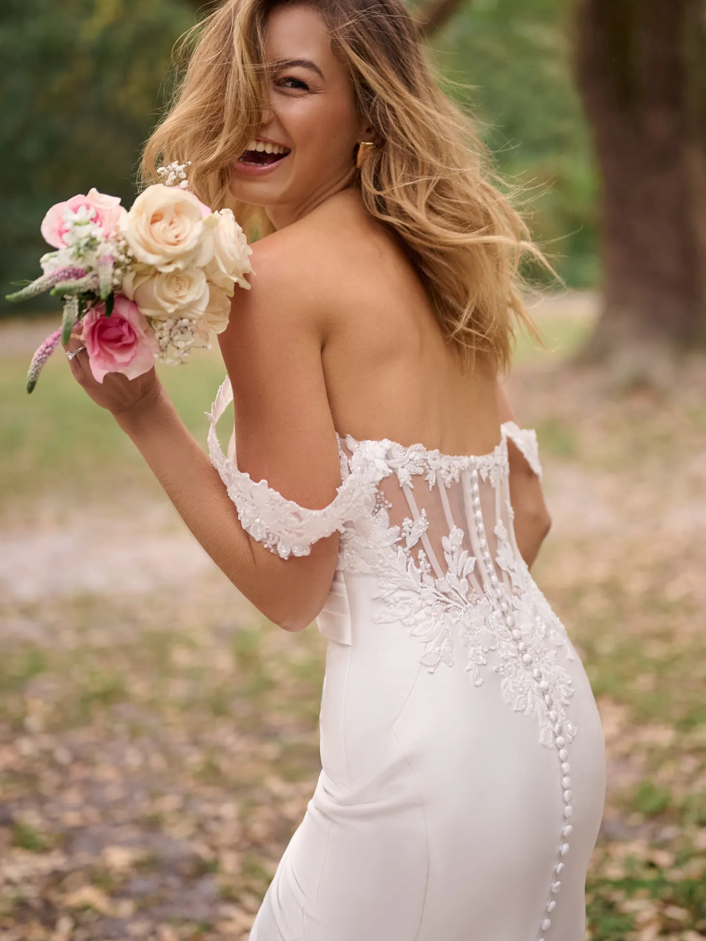 Rebecca Ingram Cindy back view lace off-shoulder dress in garden with bouquet