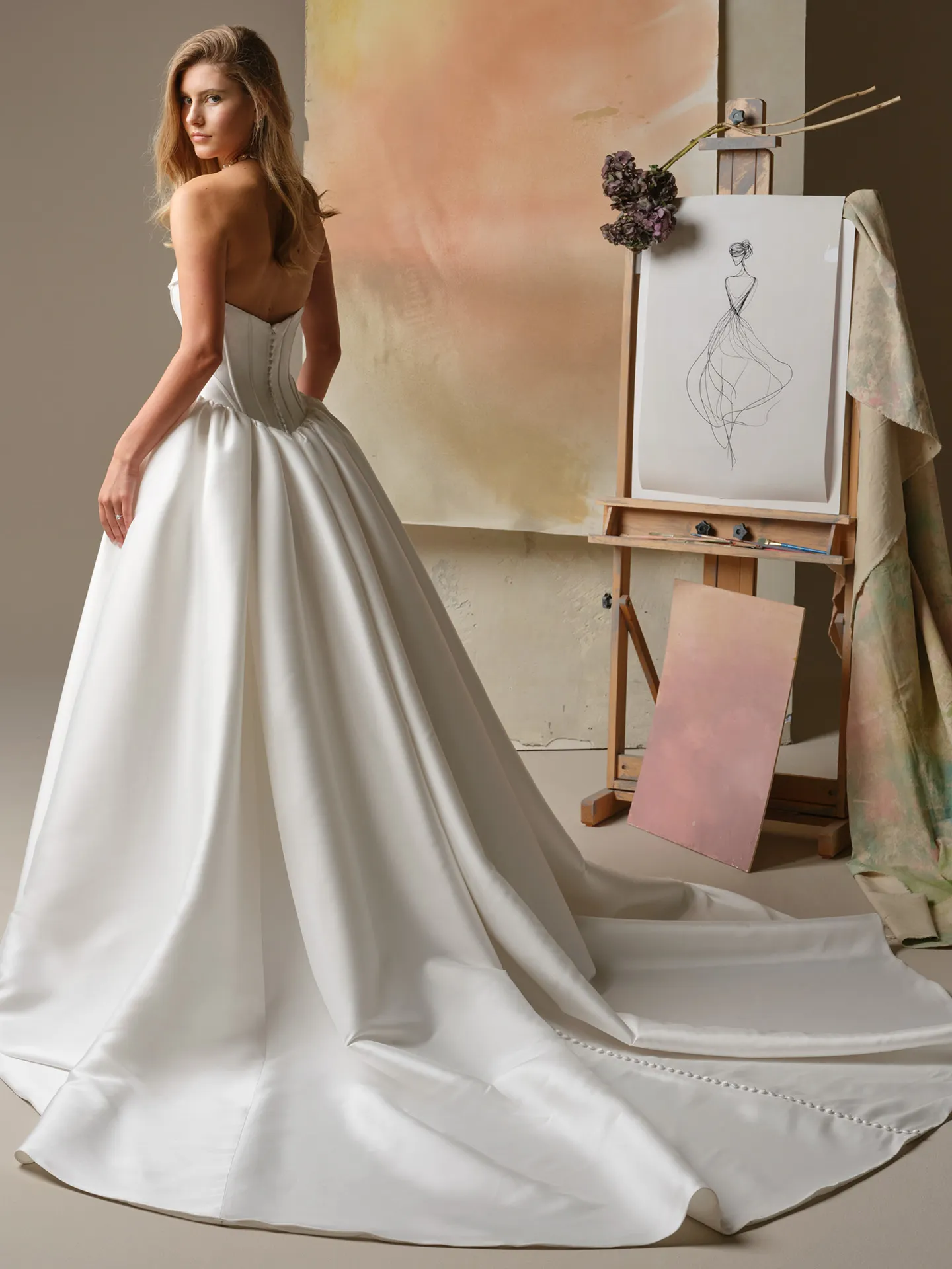 Maggie Sottero Yuma, back view ballgown with train and art easel in background.