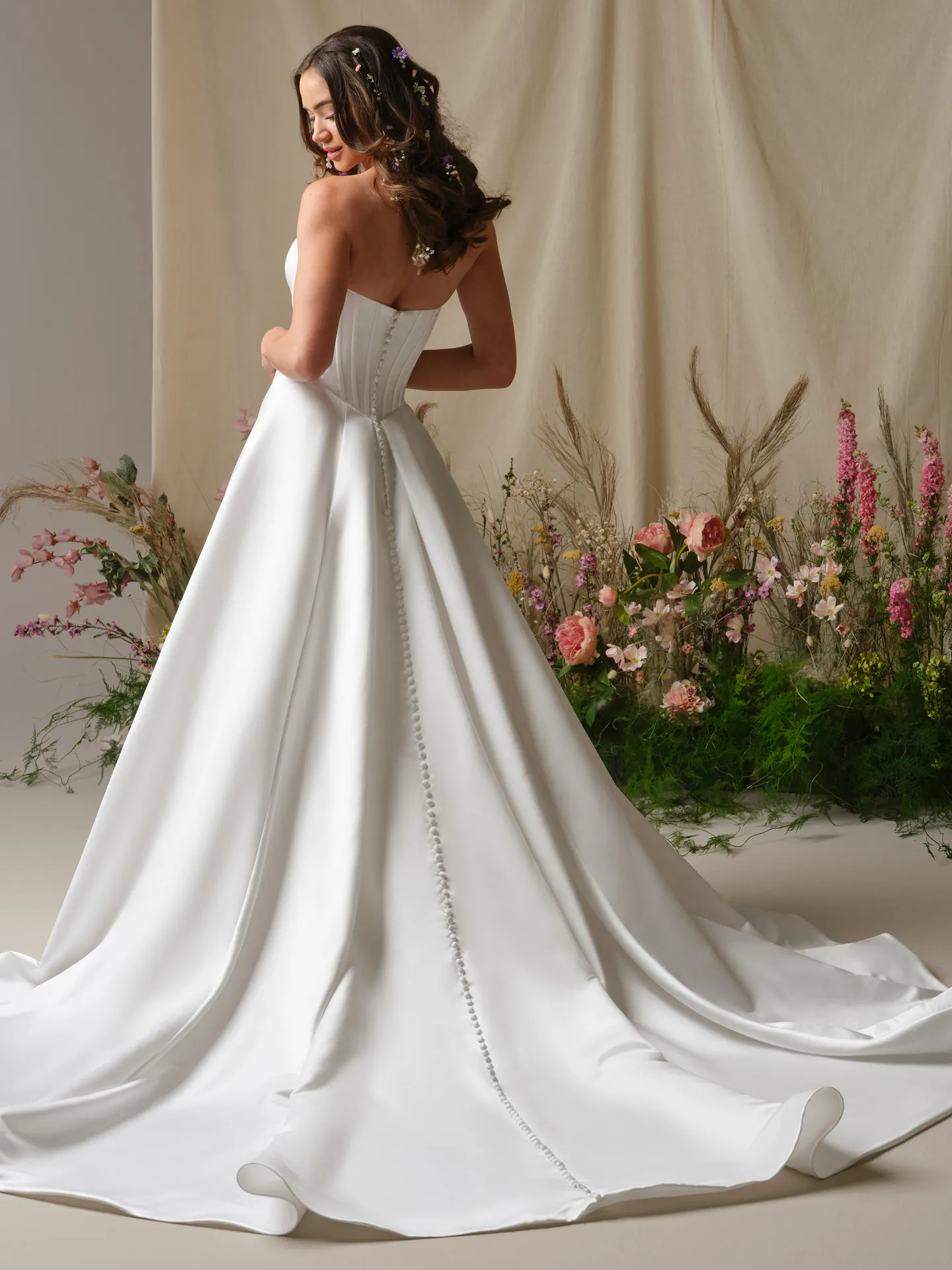 Rebecca Ingram Alexia, back view satin A-line gown with button detail and floral decor.