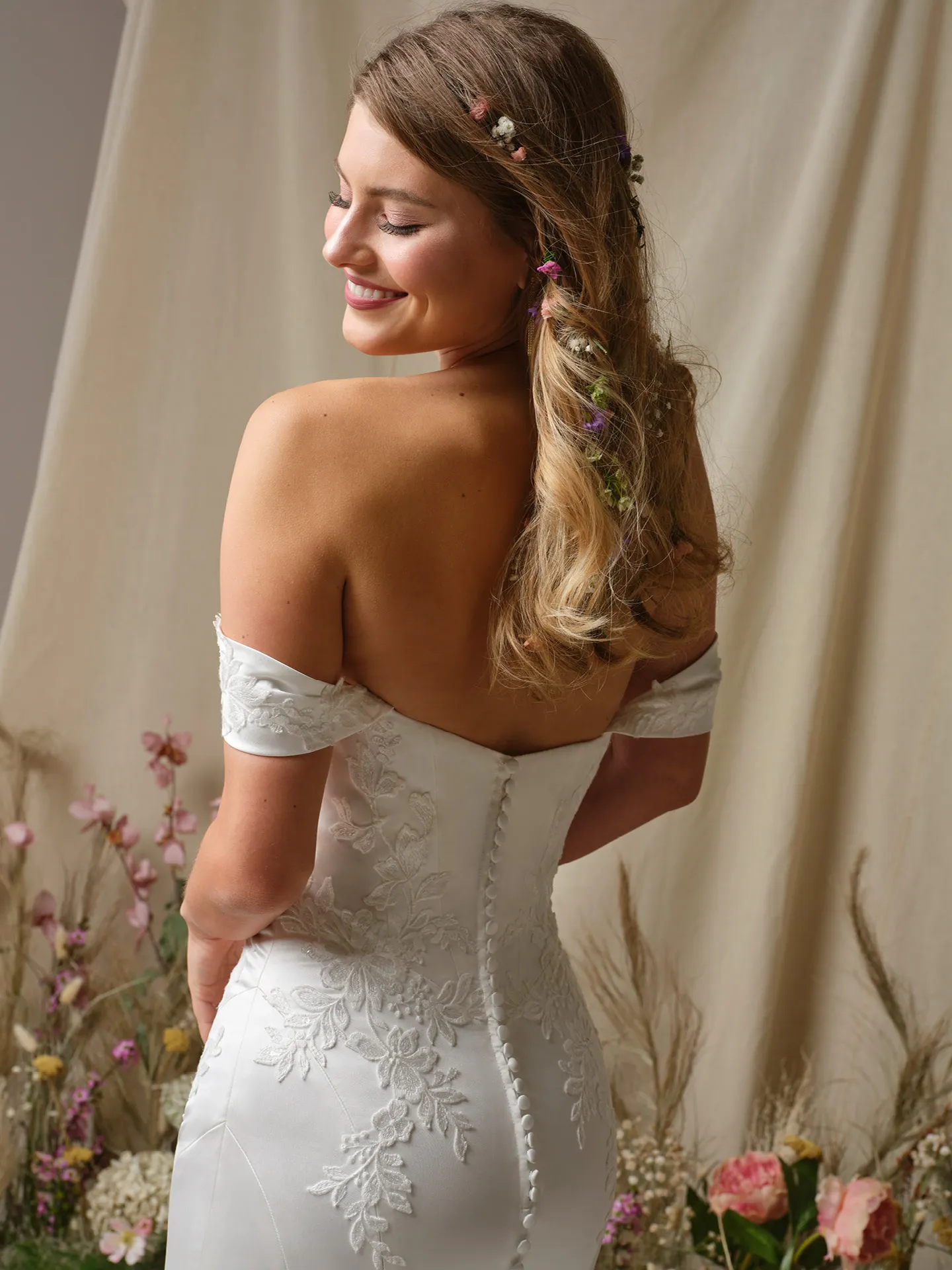 Rebecca Ingram Miley back view, off-shoulder, lace fit-and-flare dress with floral background