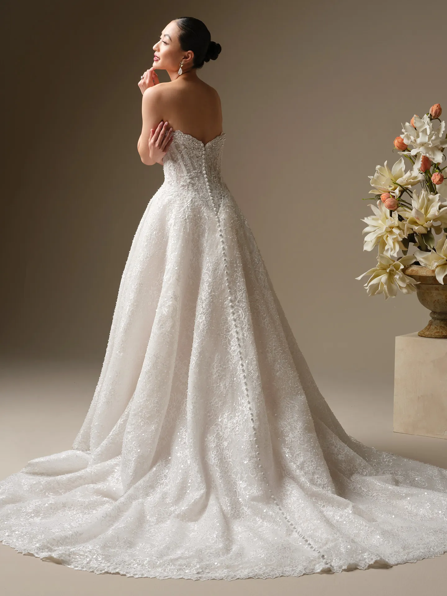 Maggie Sottero Angelica, side view, beaded A-Line wedding dress with floral backdrop.