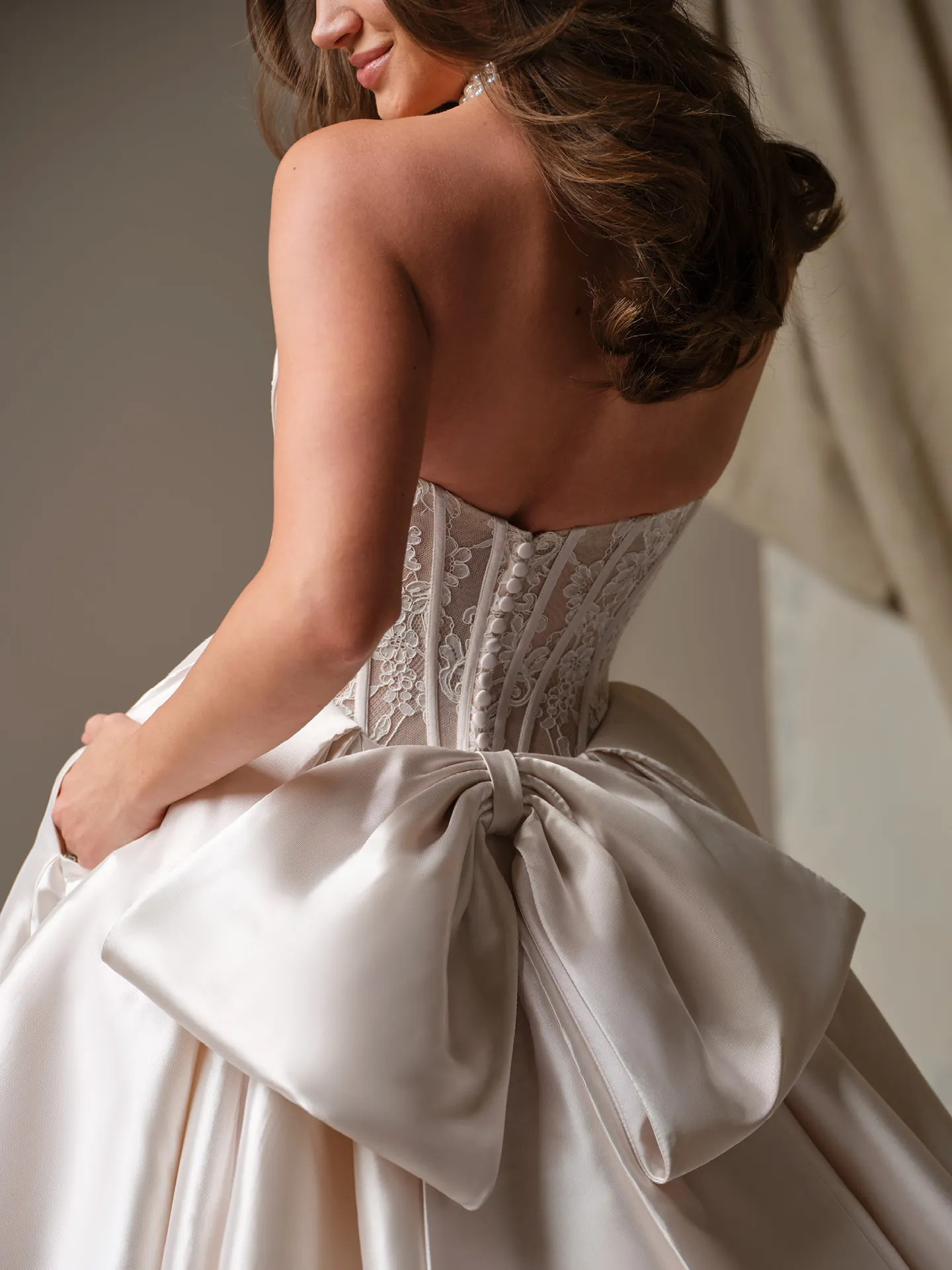 Maggie Sottero Ashland, back view with lace bodice and large bow on ballgown skirt.