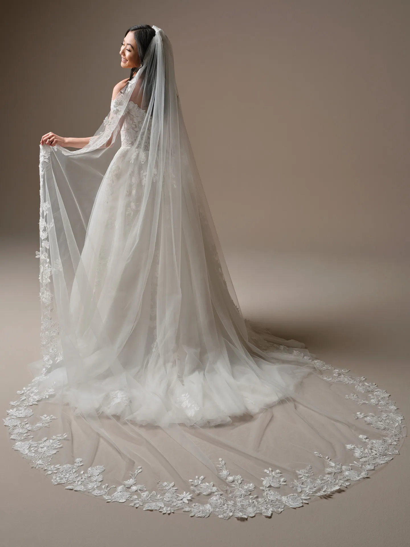 Maggie Sottero Verina, back view A-Line lace wedding dress with long train and off-shoulder design.