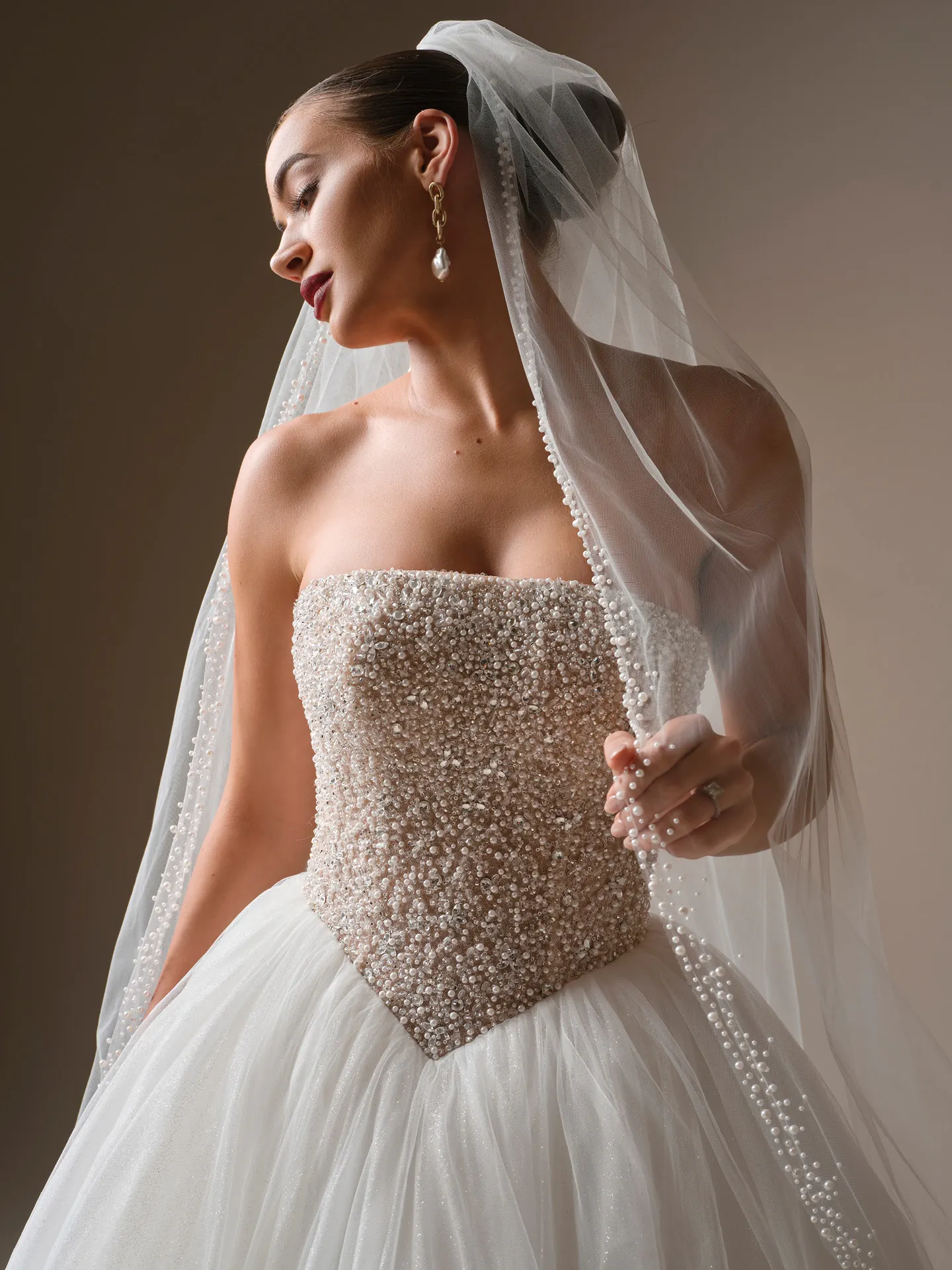 Sottero and Midgley veil with pearl edge worn over an embellished strapless dress, side view.